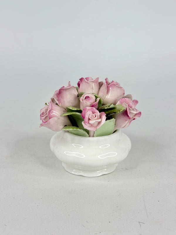 Small white vase with pink roses on a light gray background