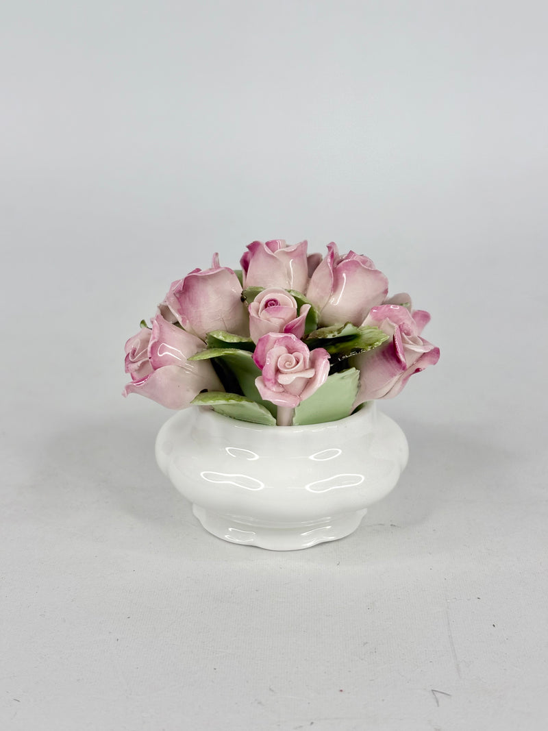 Small white vase with pink roses on a light gray background