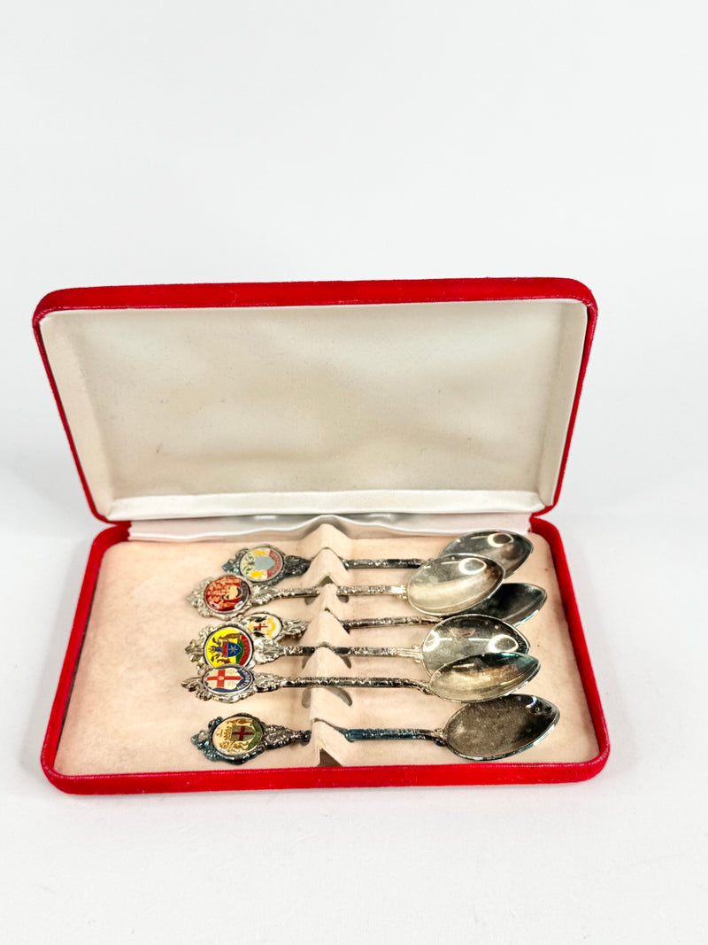 Set of silver spoons with enameled handles in a red velvet box on a white background