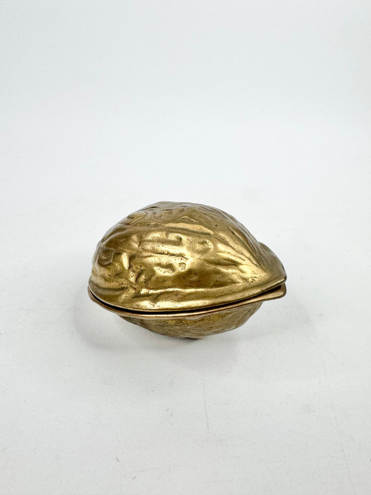 Gold-colored object shaped like a walnut on a white background