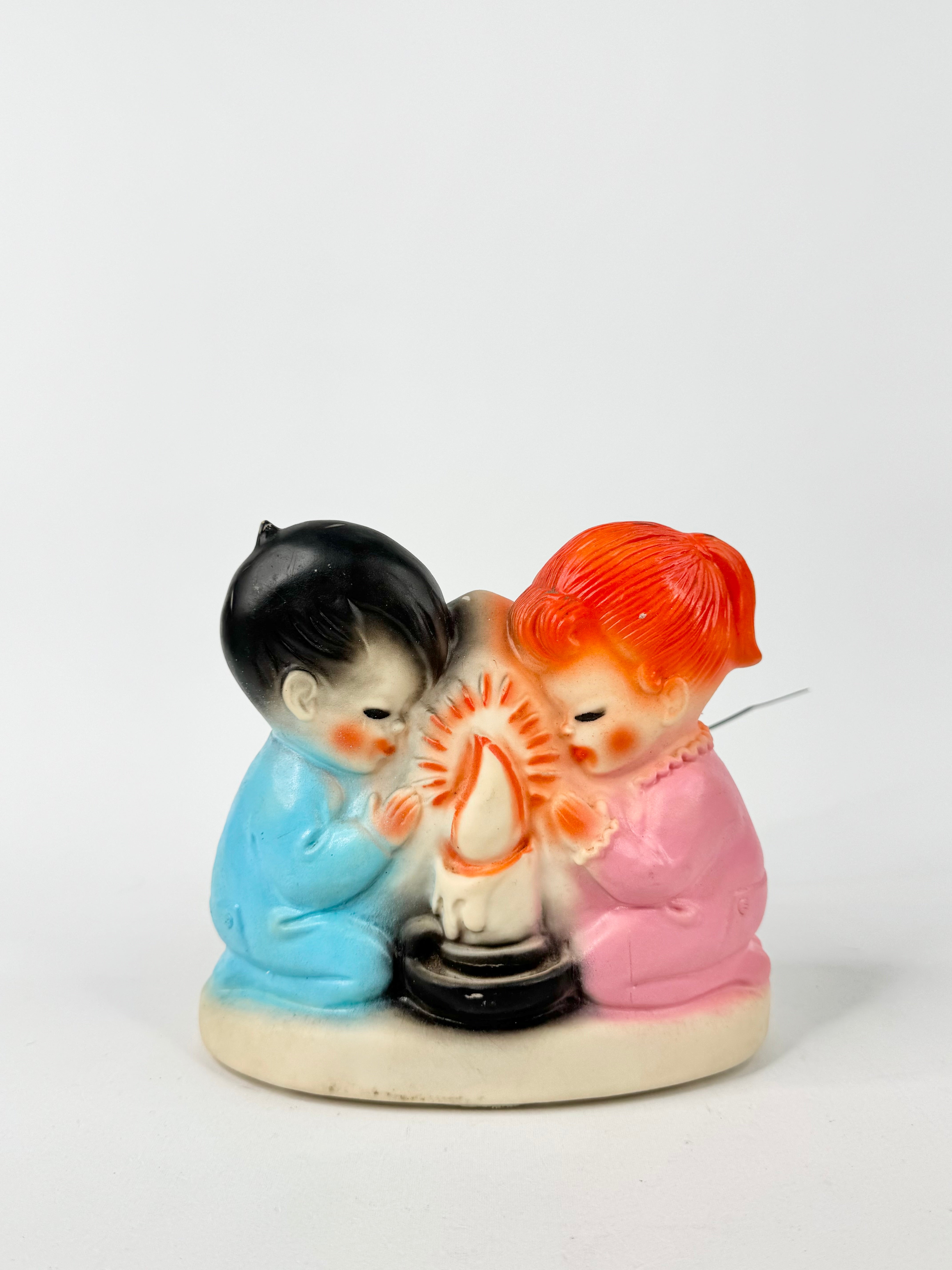 Decorative figurine of two children with a candle on a white background
