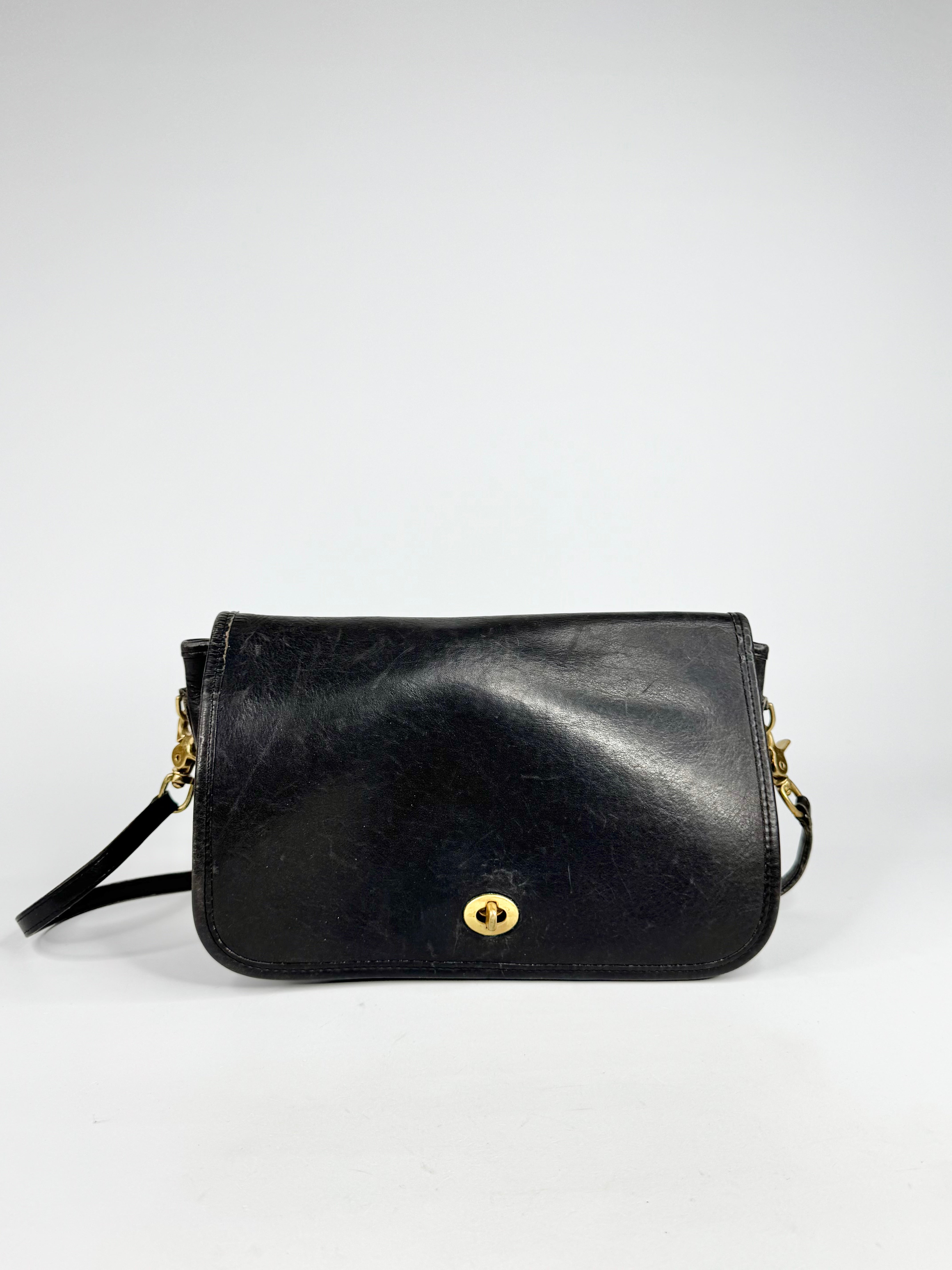 Black leather handbag with gold accents on a white background