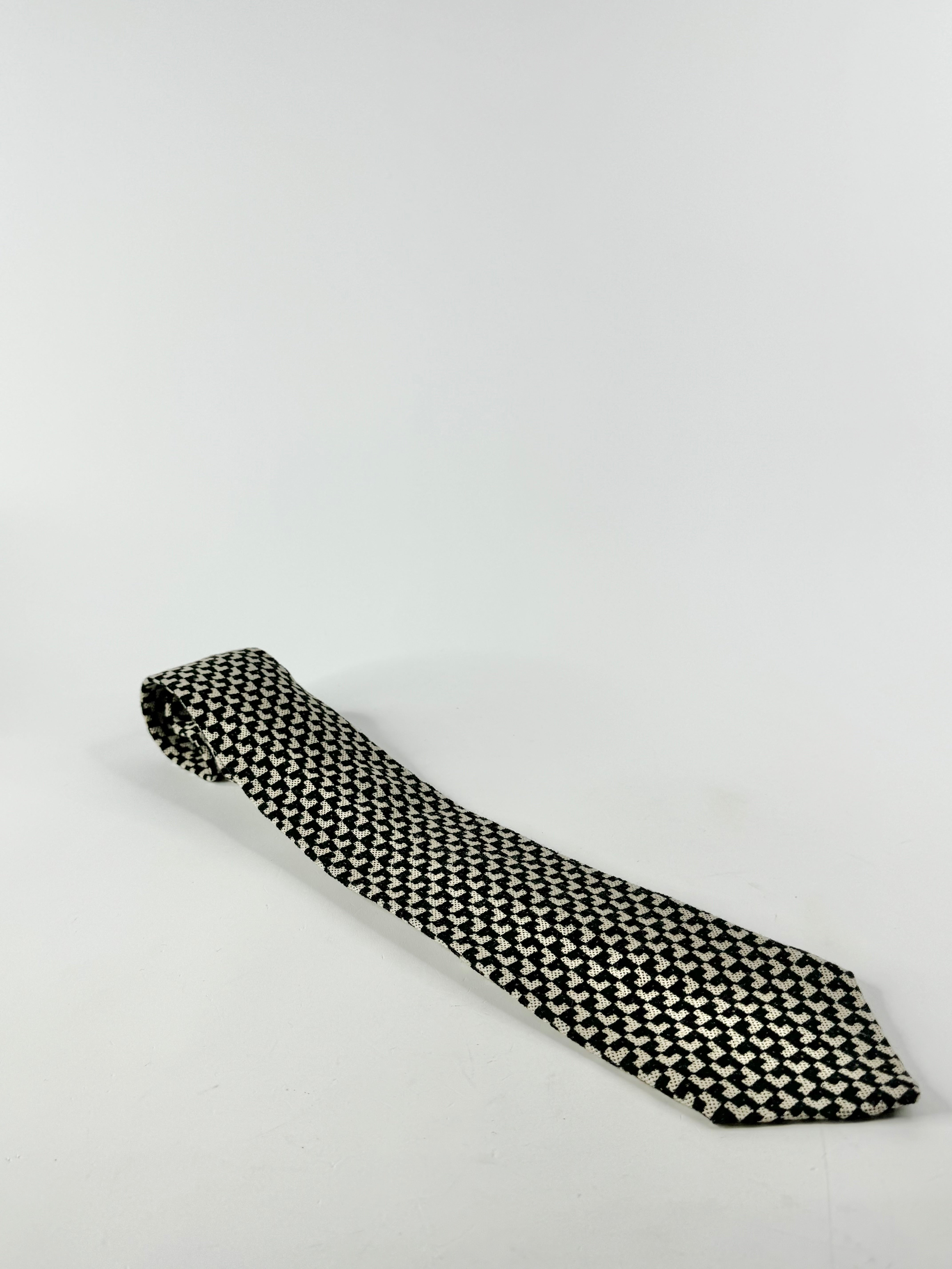 A black and white patterned wool tie on a white background.