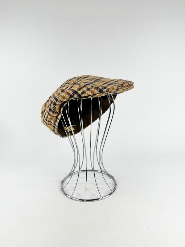 Plaid cap on a wire stand against a white background