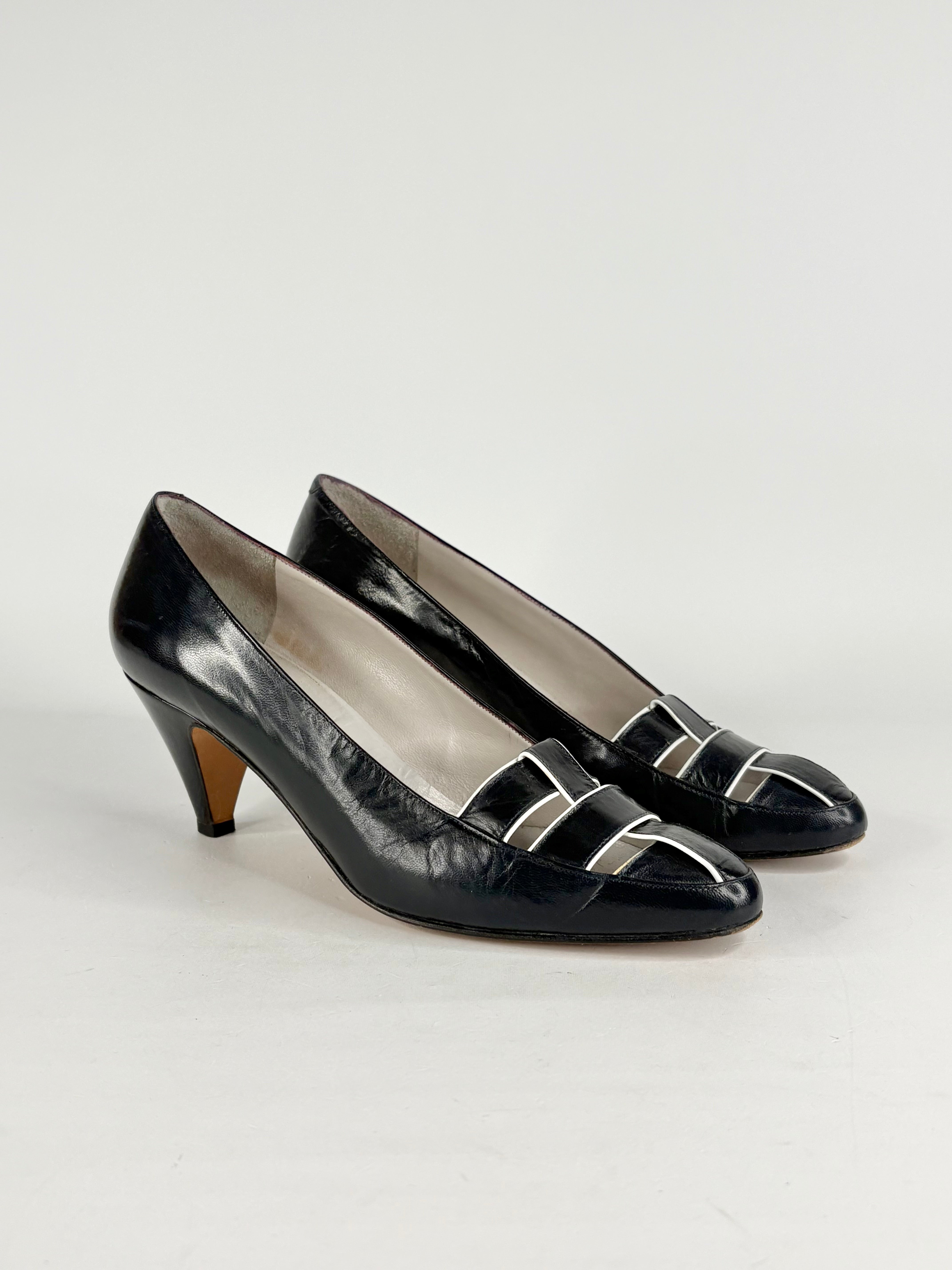 Pair of black high-heeled shoes with silver buckles on a white background