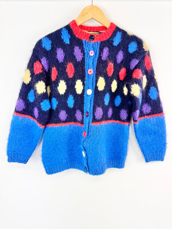 Colorful polka dot cardigan on a hanger against a white background