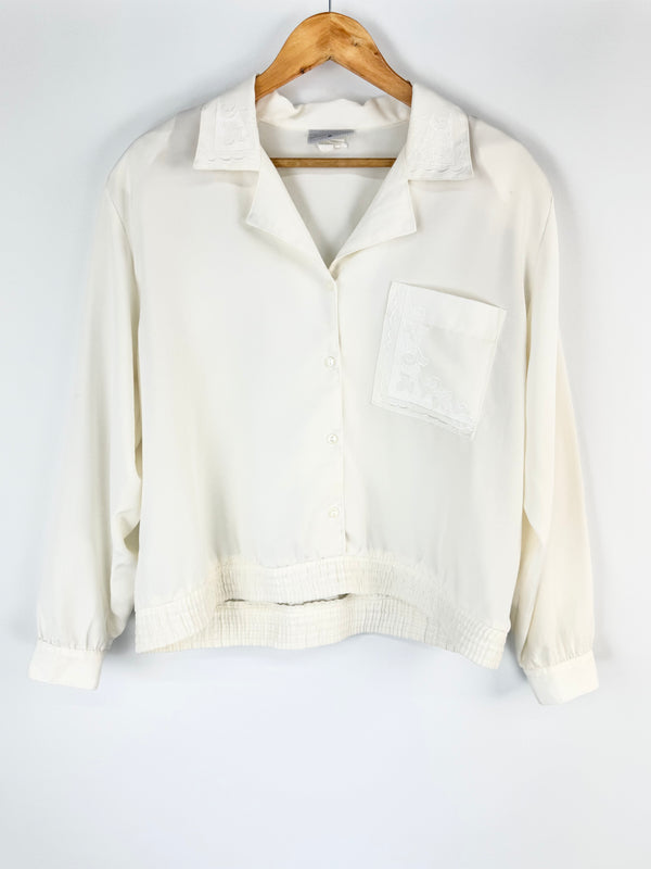 White blouse on a wooden hanger against a white background