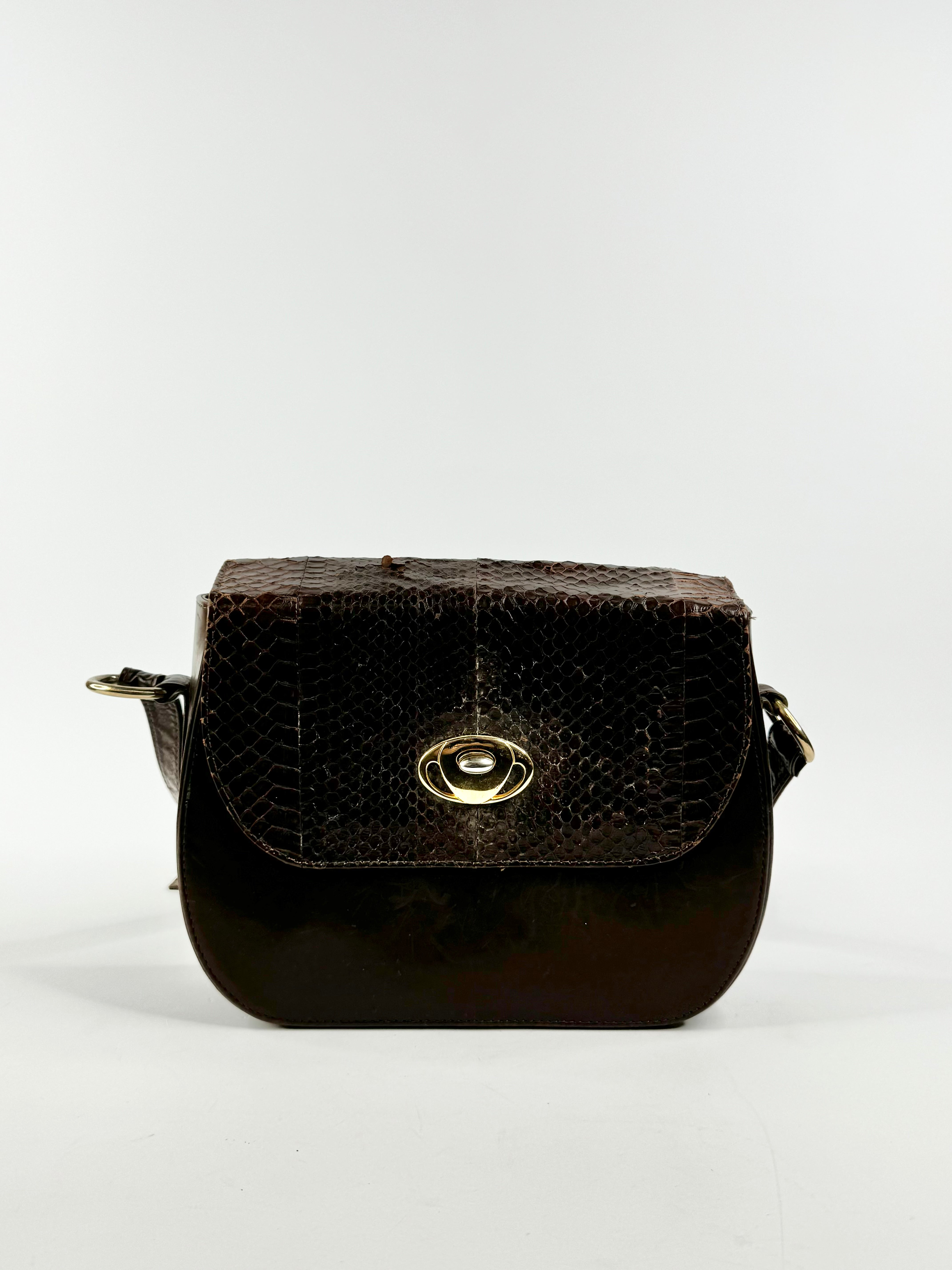 A brown leather cross body bag with a crocodile pattern on the flap and a large gold-toned fastening.