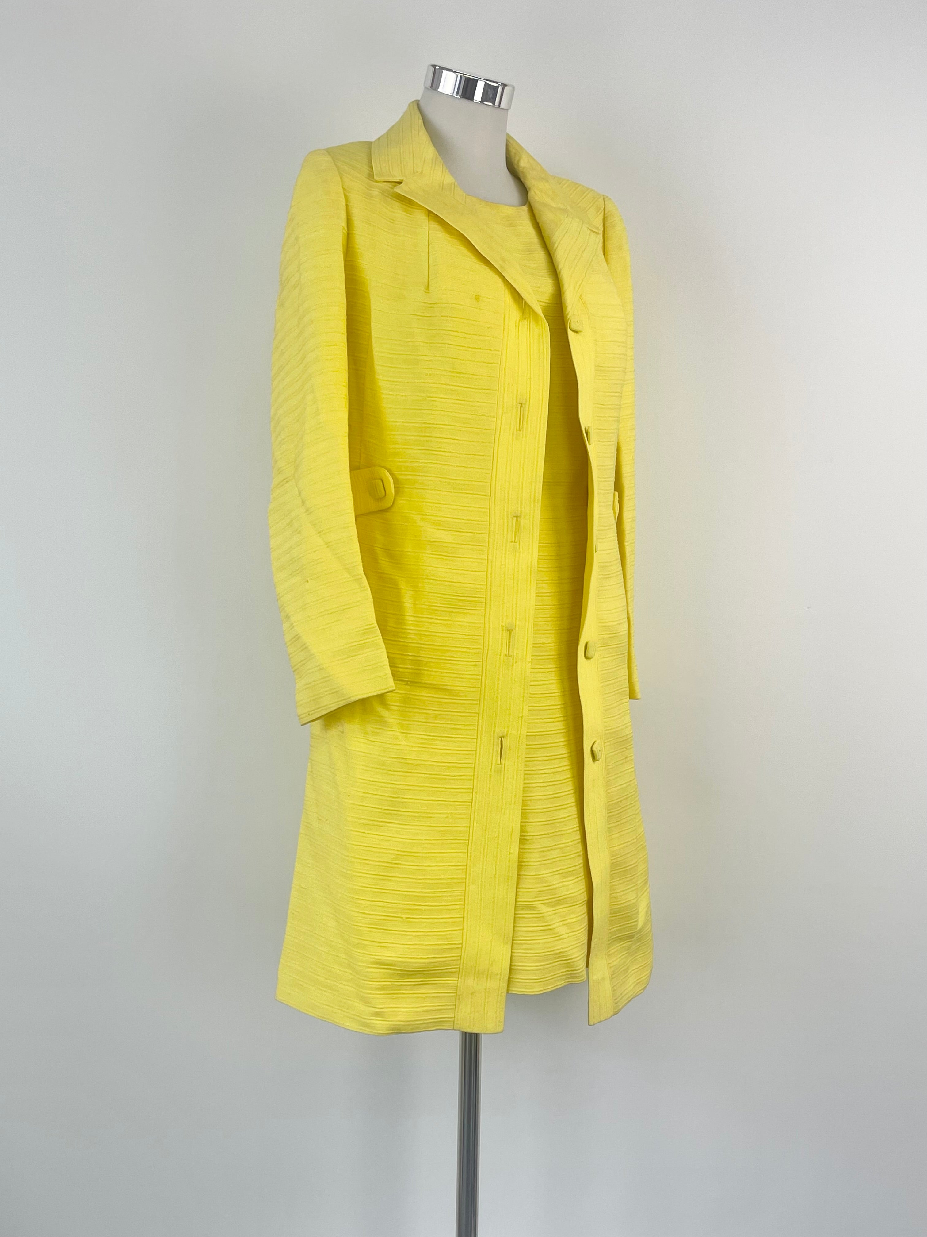A vibrant yellow ribbed coat and dress set on a mannequin, featuring a midi length and short sleeves.