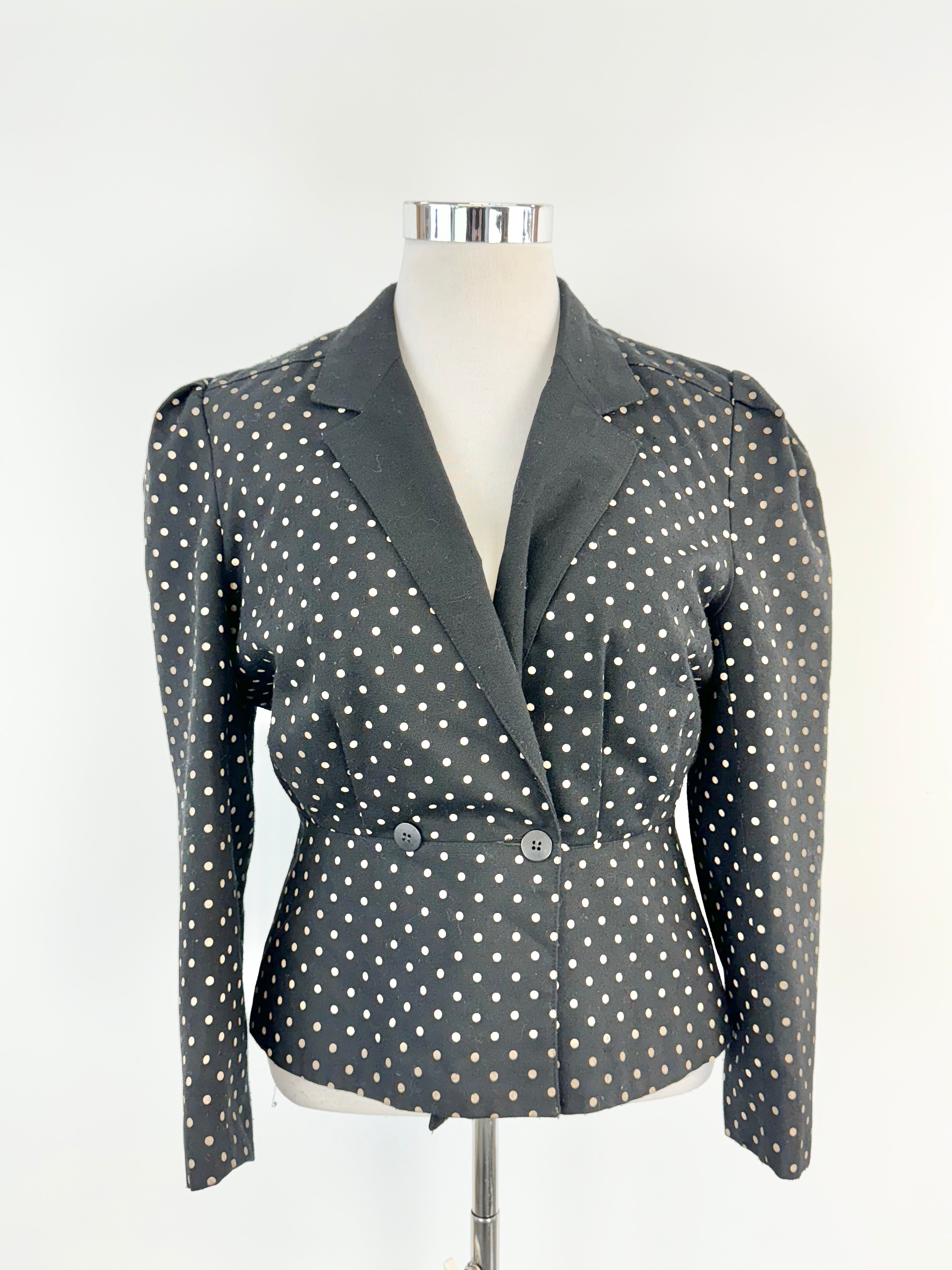 A vintage black and beige dotted jacket with a mandarin collar and double fastening, displayed on a mannequin.