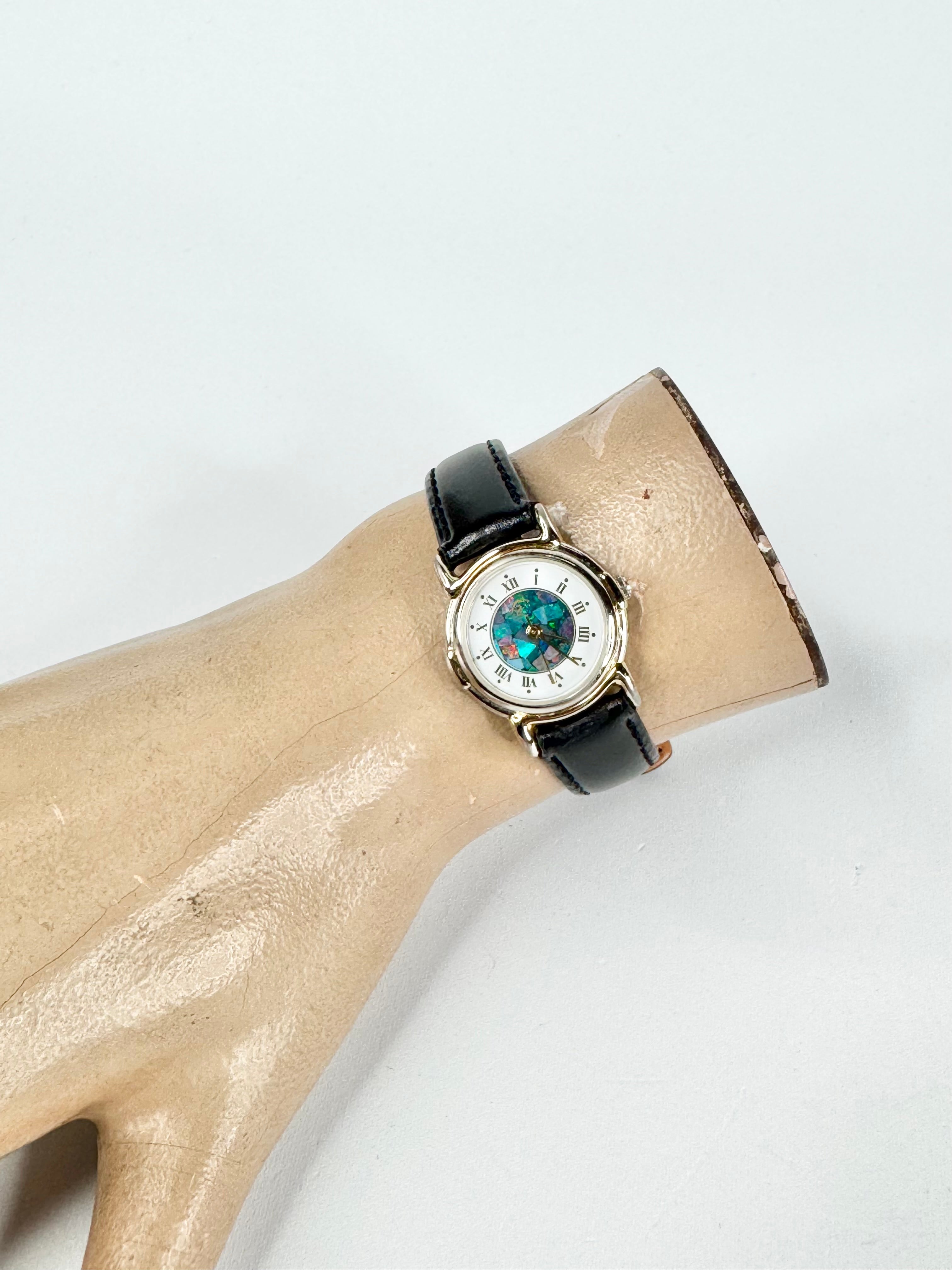 Watch with a black strap on a mannequin arm against a white background