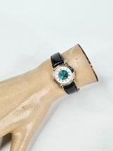 Watch with a black strap on a mannequin arm against a white background