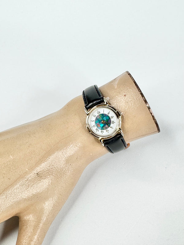 Watch with a black strap on a mannequin arm against a white background