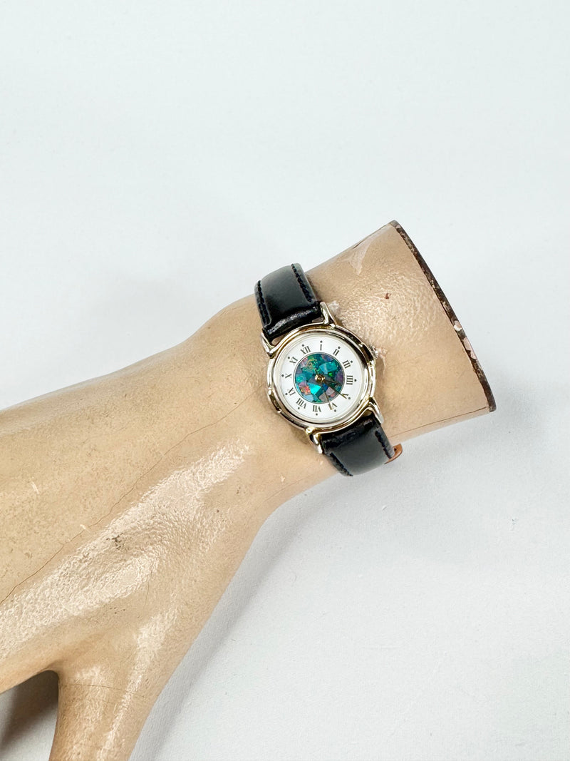 Watch with a black strap on a mannequin arm against a white background