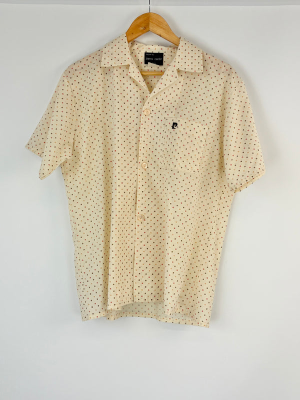 Cream short-sleeve shirt with subtle pattern on a hanger against a white background
