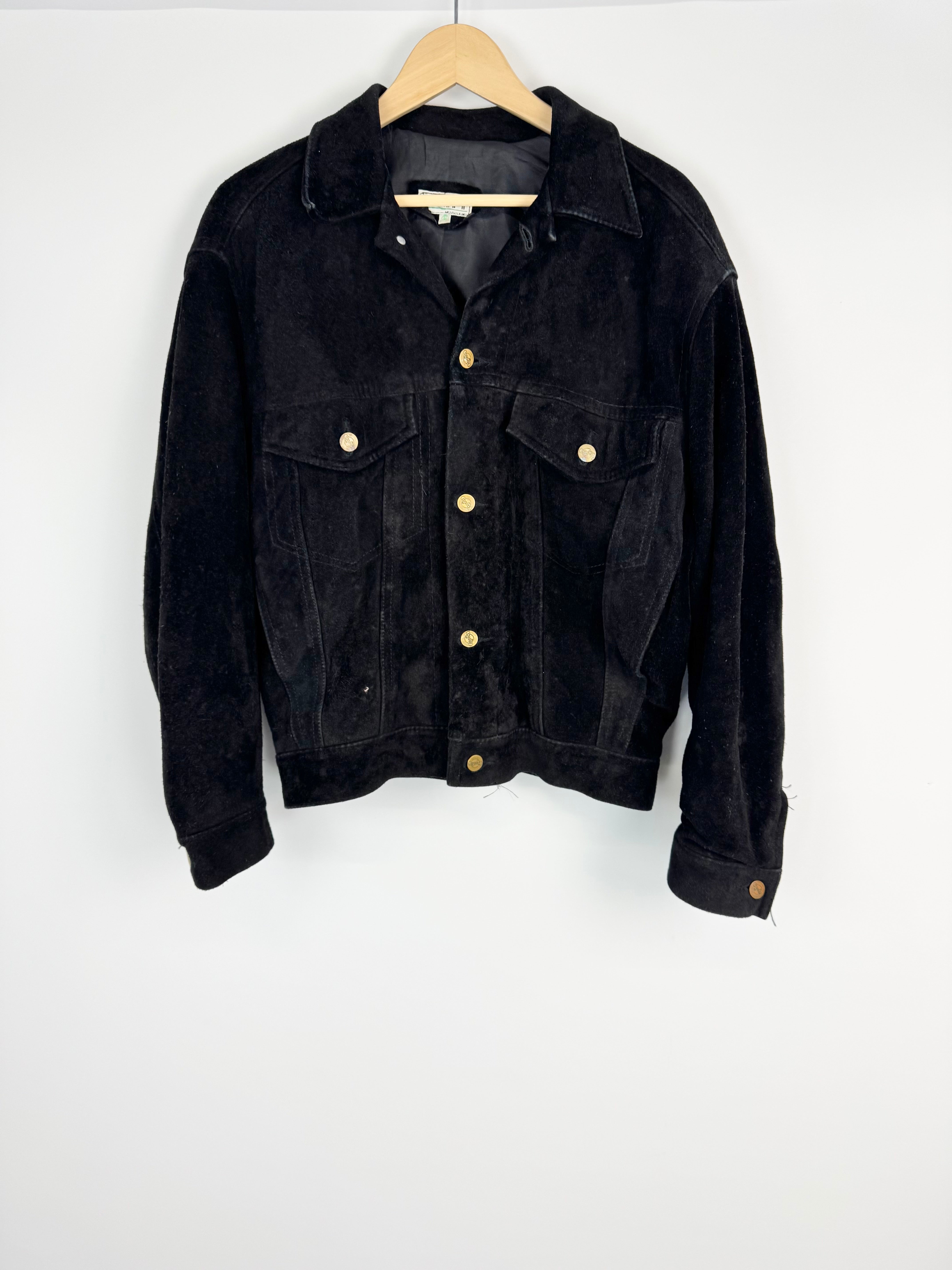 Black jacket with gold buttons on a wooden hanger against a white background