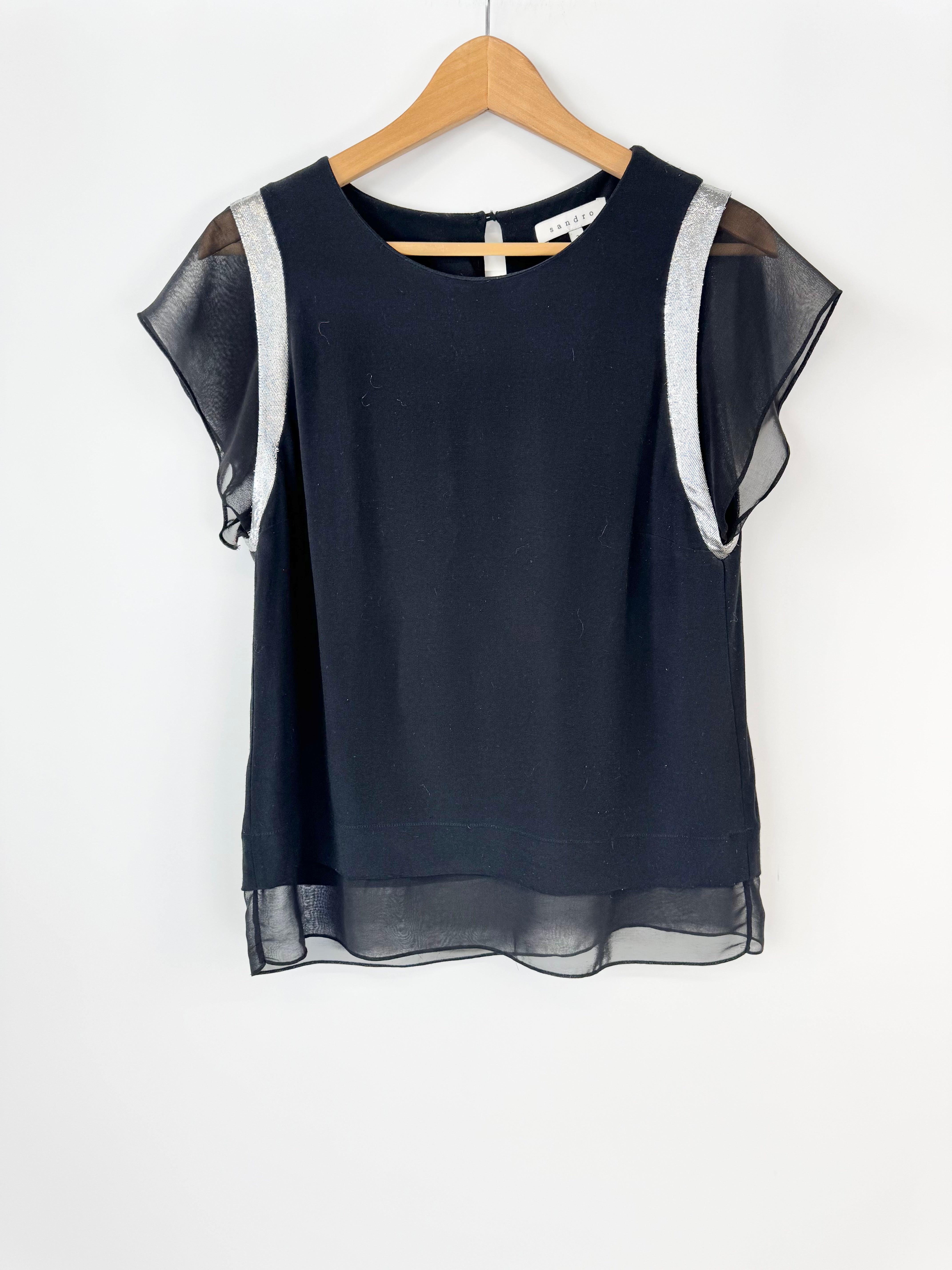 Black blouse with sheer sleeves on a wooden hanger against a white background