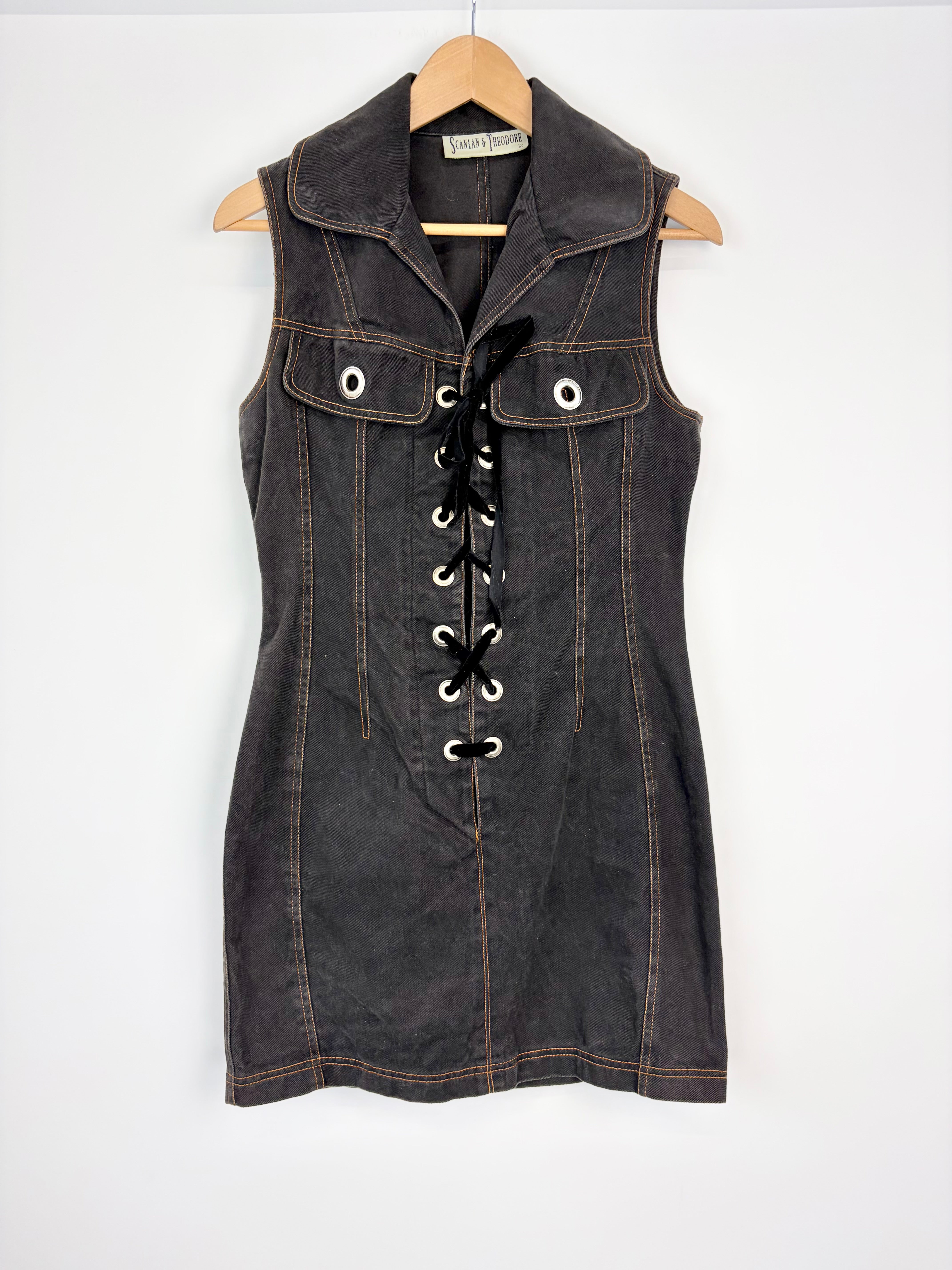 Denim vest with lace-up front on a hanger against a white background
