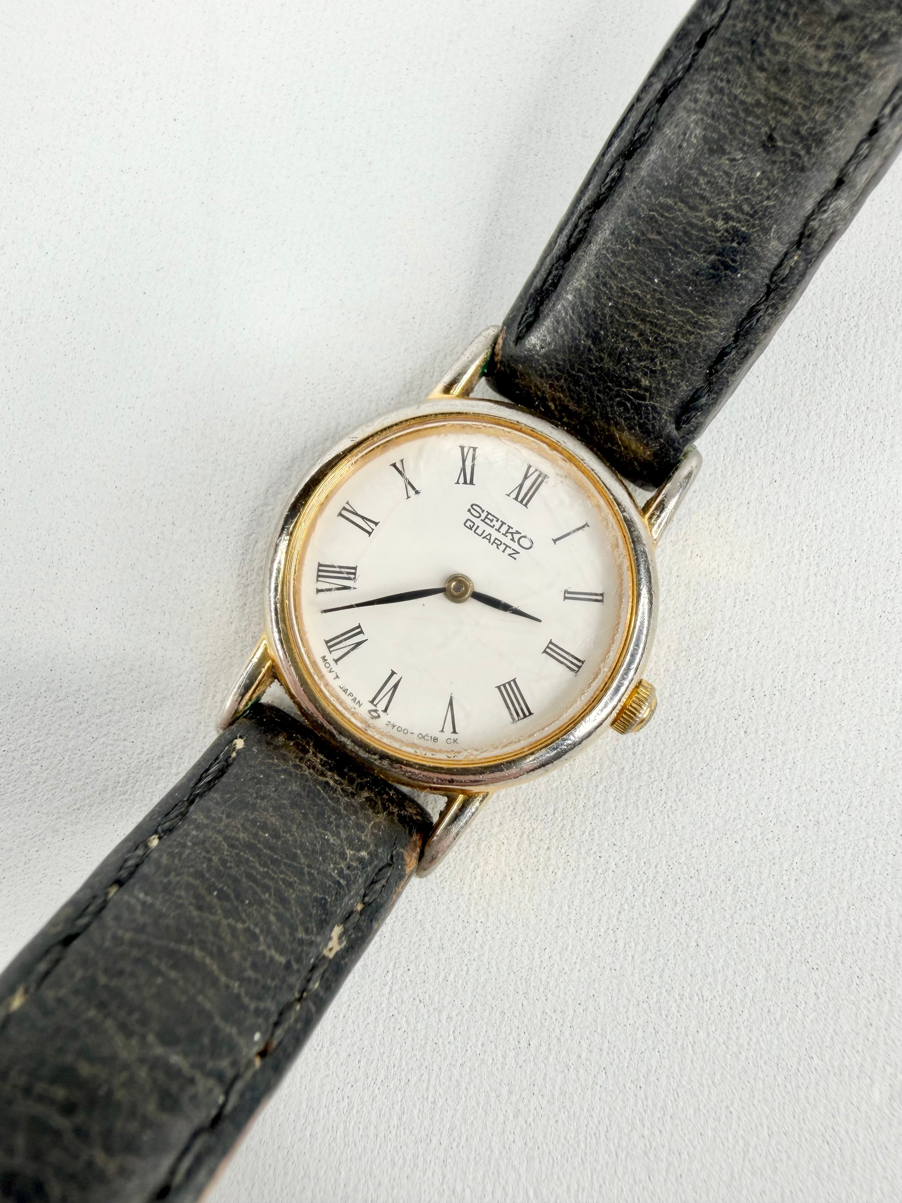 Vintage wristwatch with black leather strap on a white background