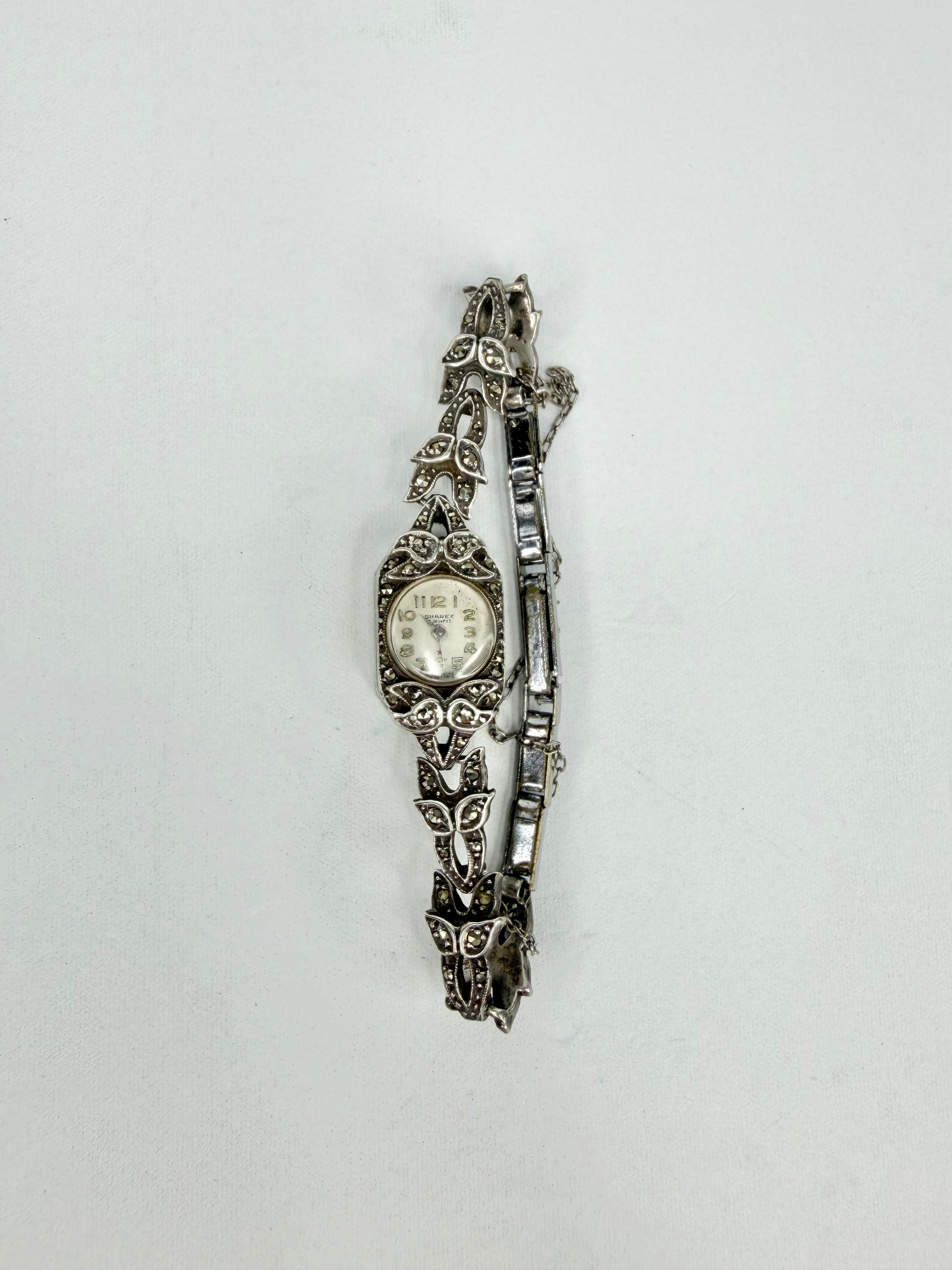 Silver watch with decorative band on a light gray background