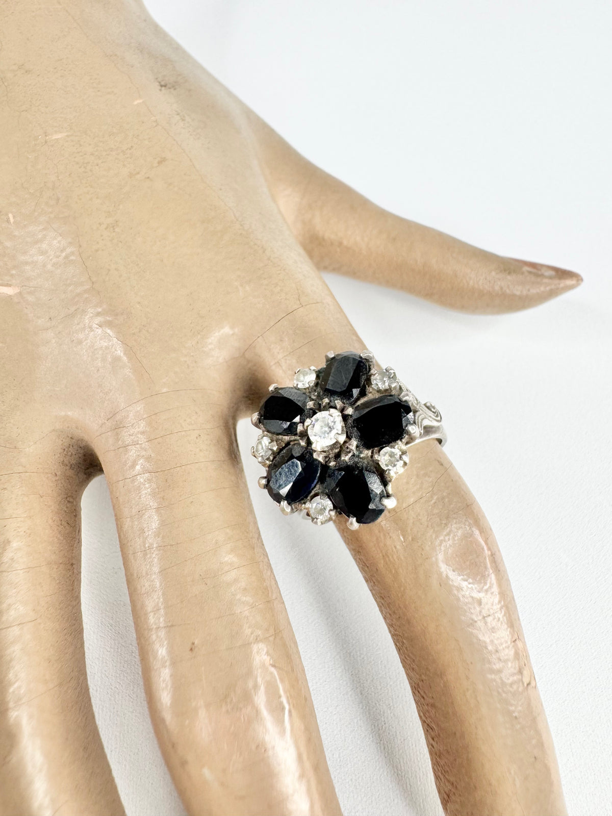 Ring with black gemstones and clear stones on a mannequin hand