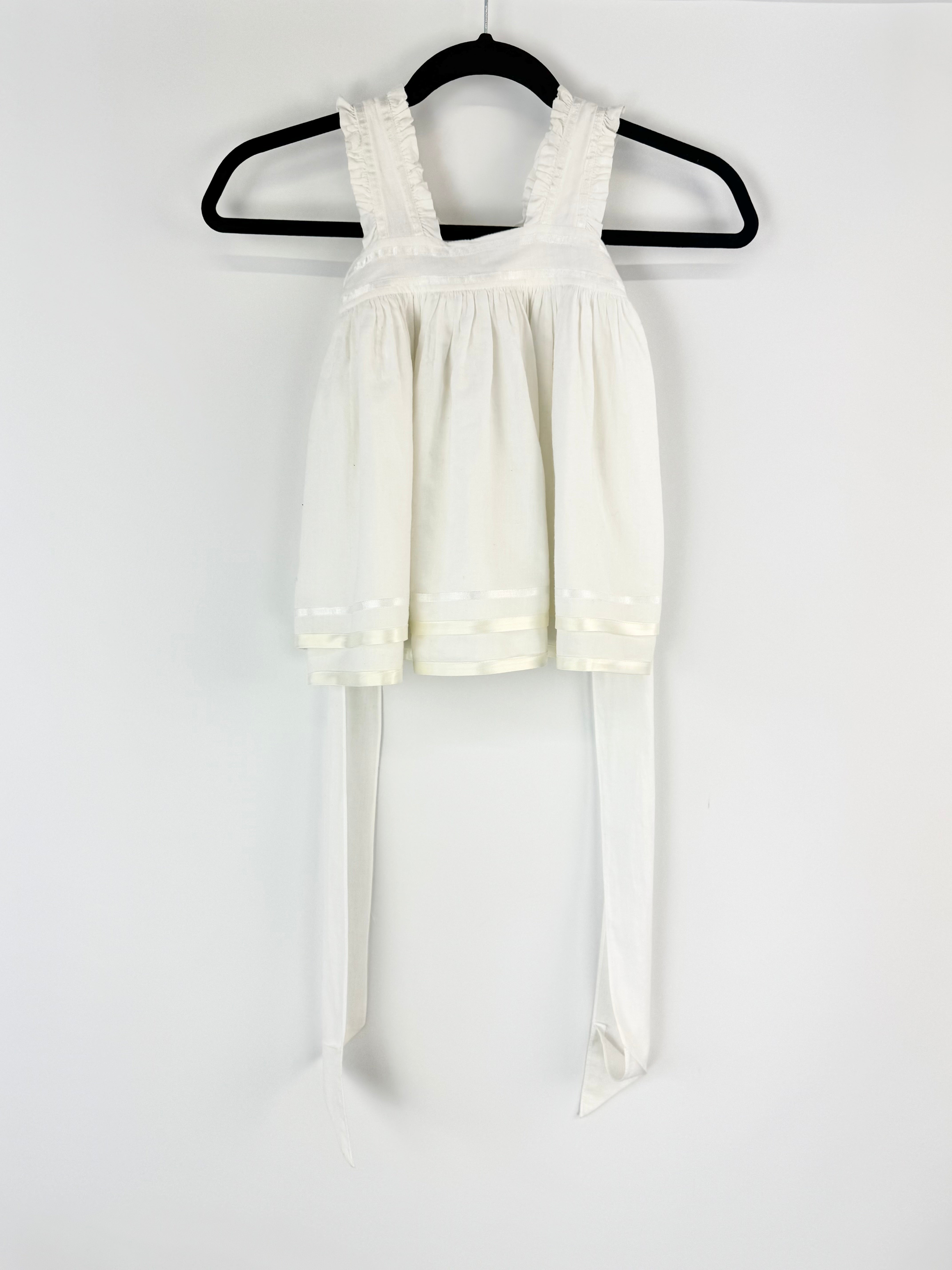 White dress with lace straps on a hanger against a white background