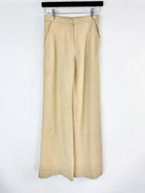 Beige wide-leg pants hanging on a rack against a white background