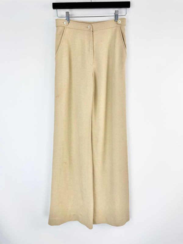 Beige wide-leg pants hanging on a rack against a white background