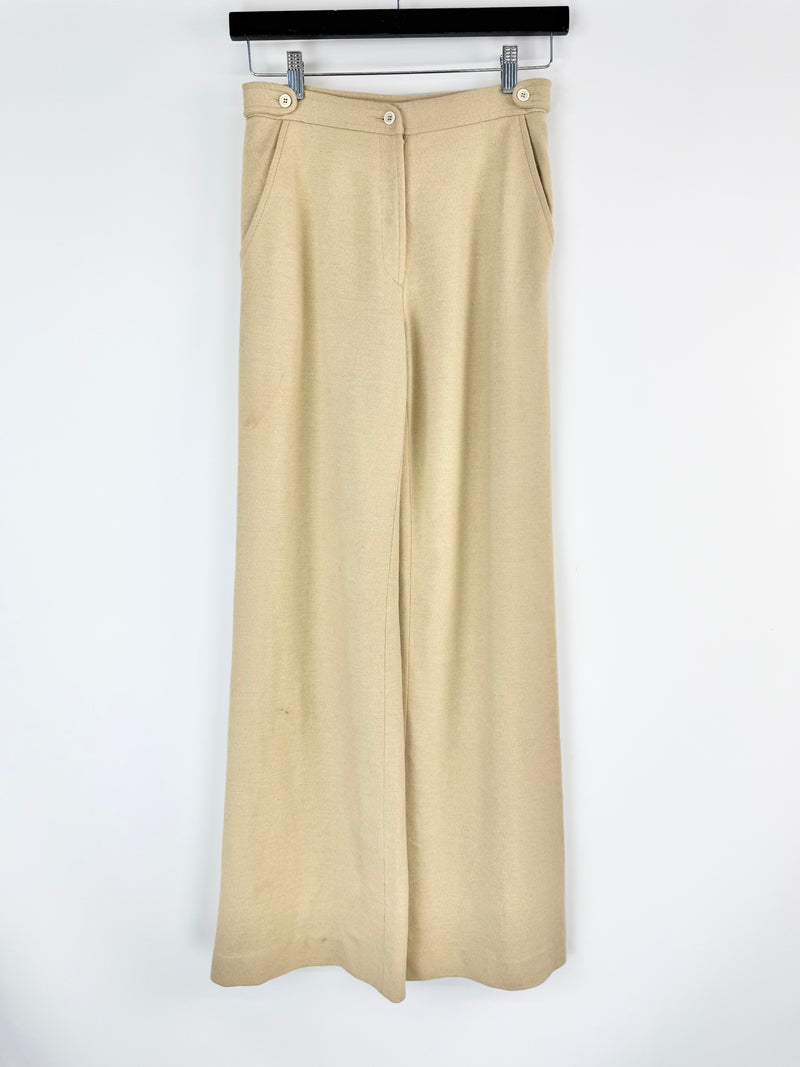 Beige wide-leg pants hanging on a rack against a white background