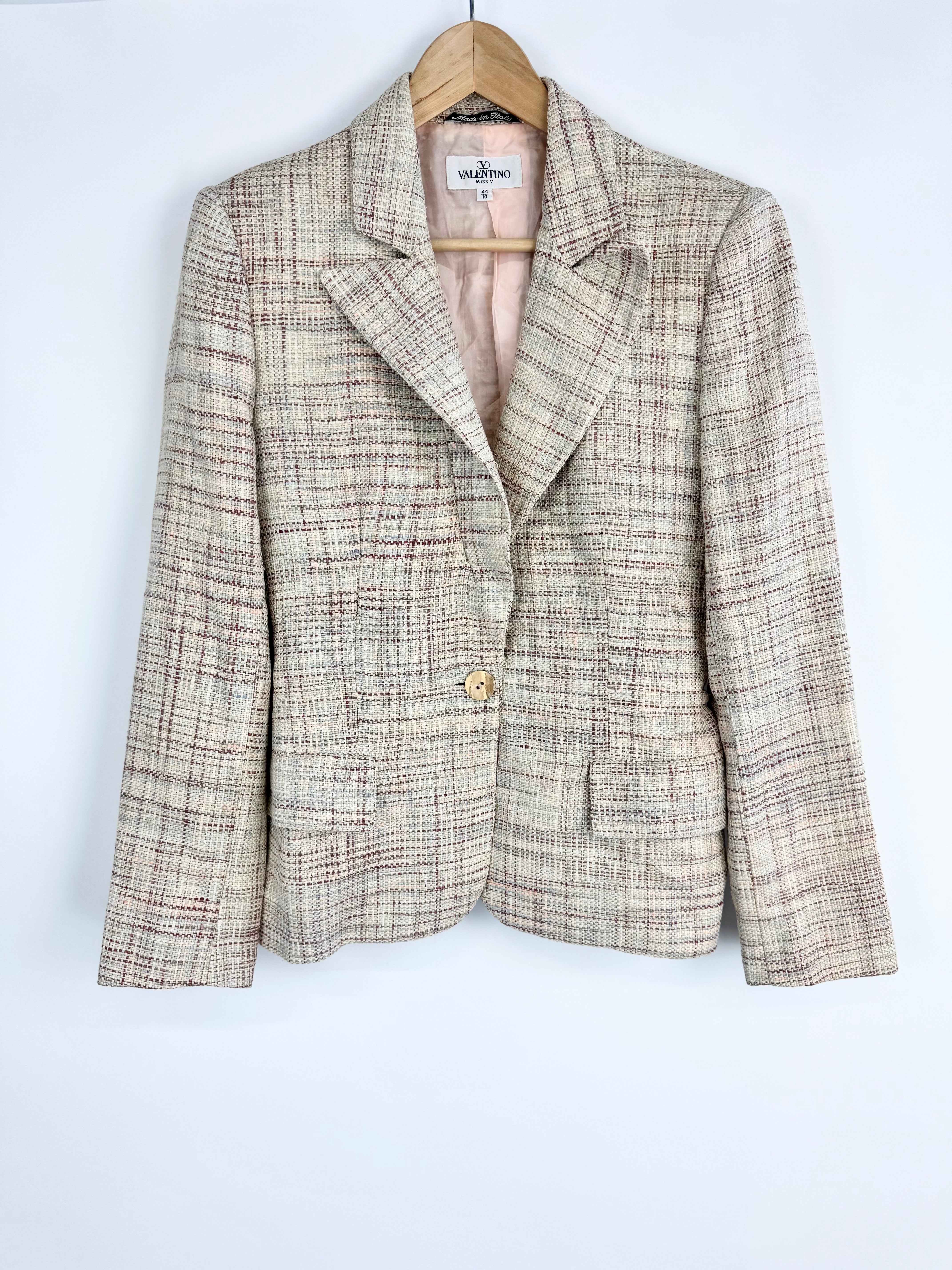Plaid blazer on a hanger against a light blue background