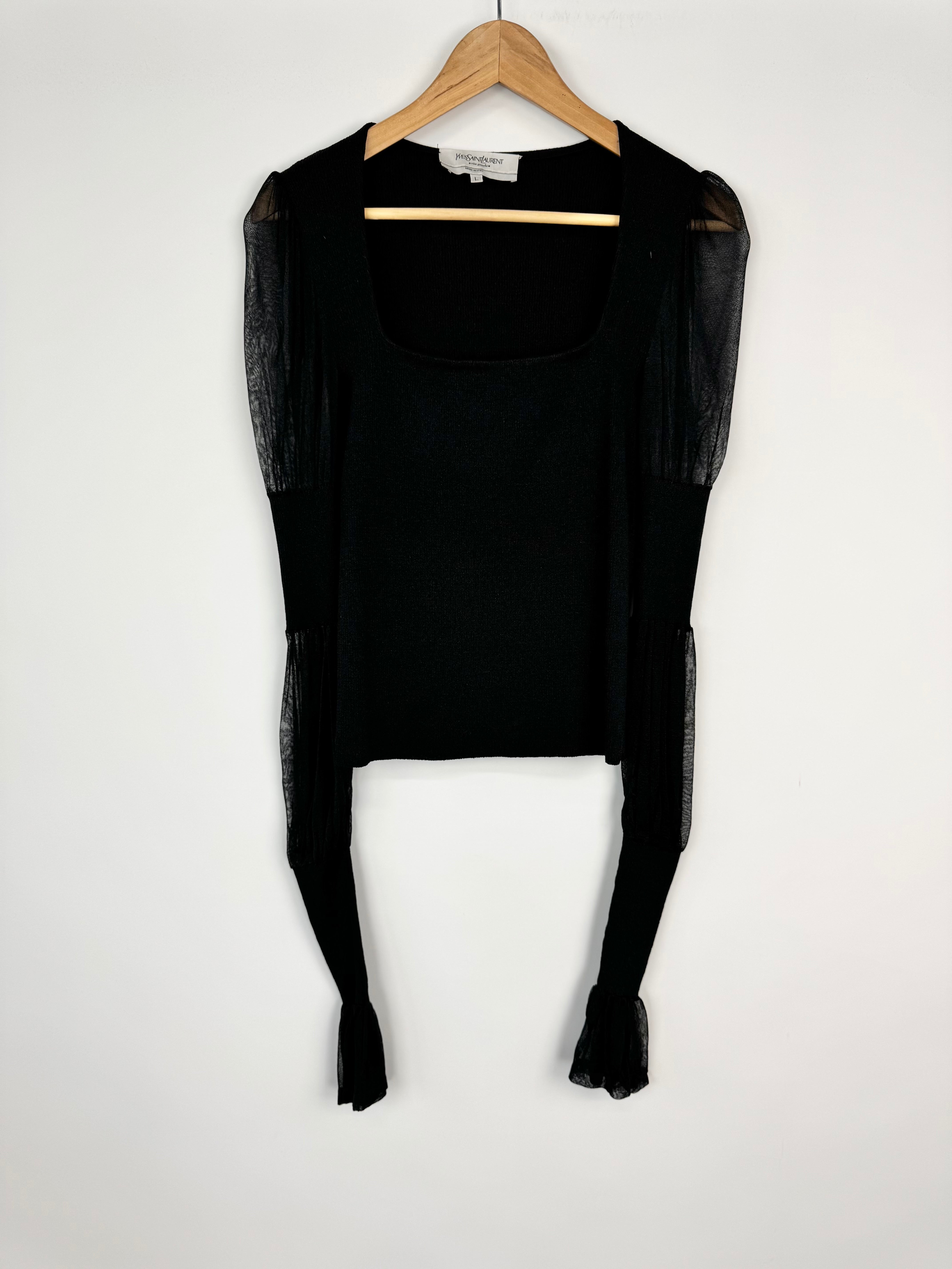 Black long-sleeve top on a hanger against a white background
