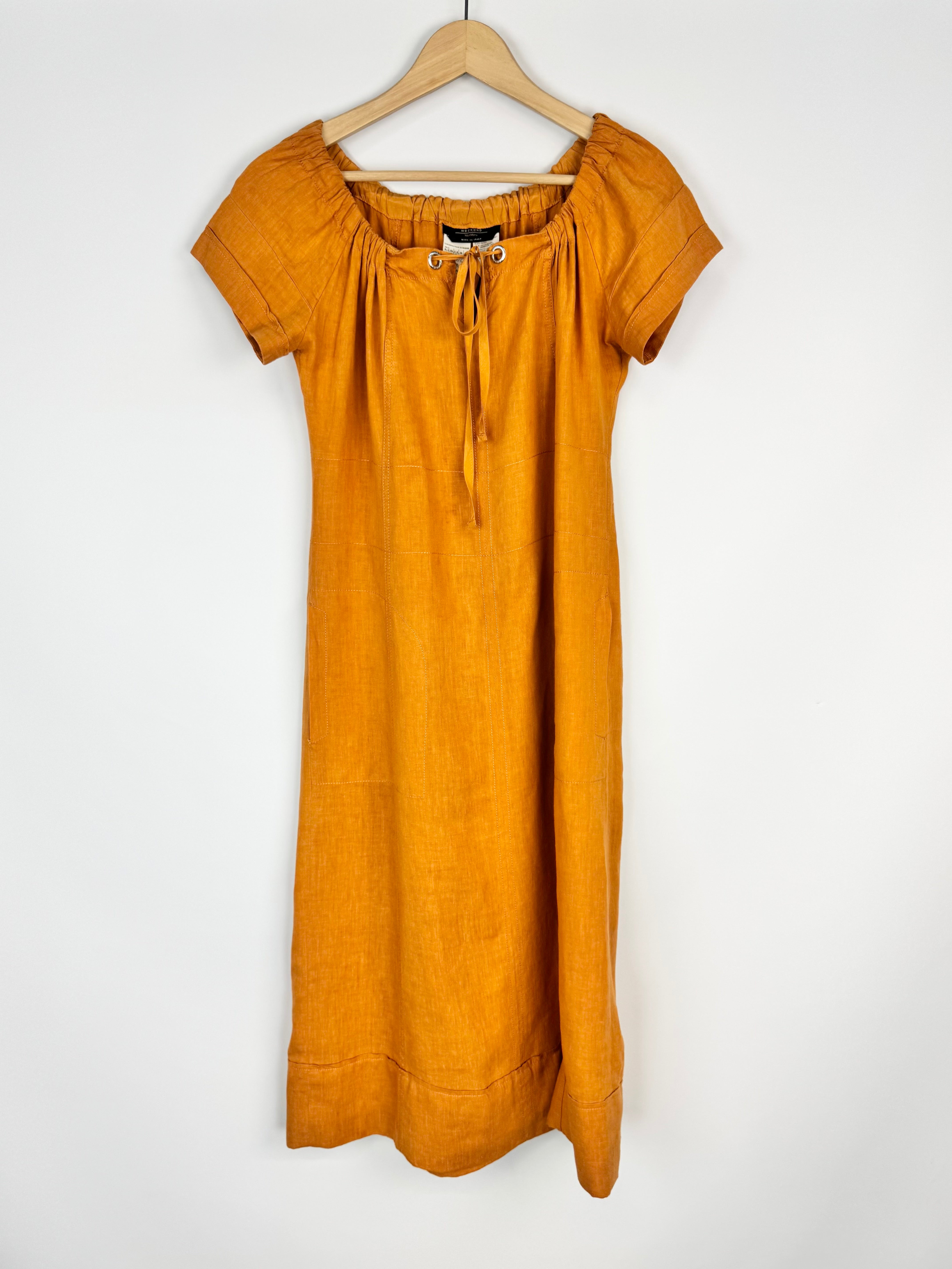 Mustard yellow dress on a hanger against a white background