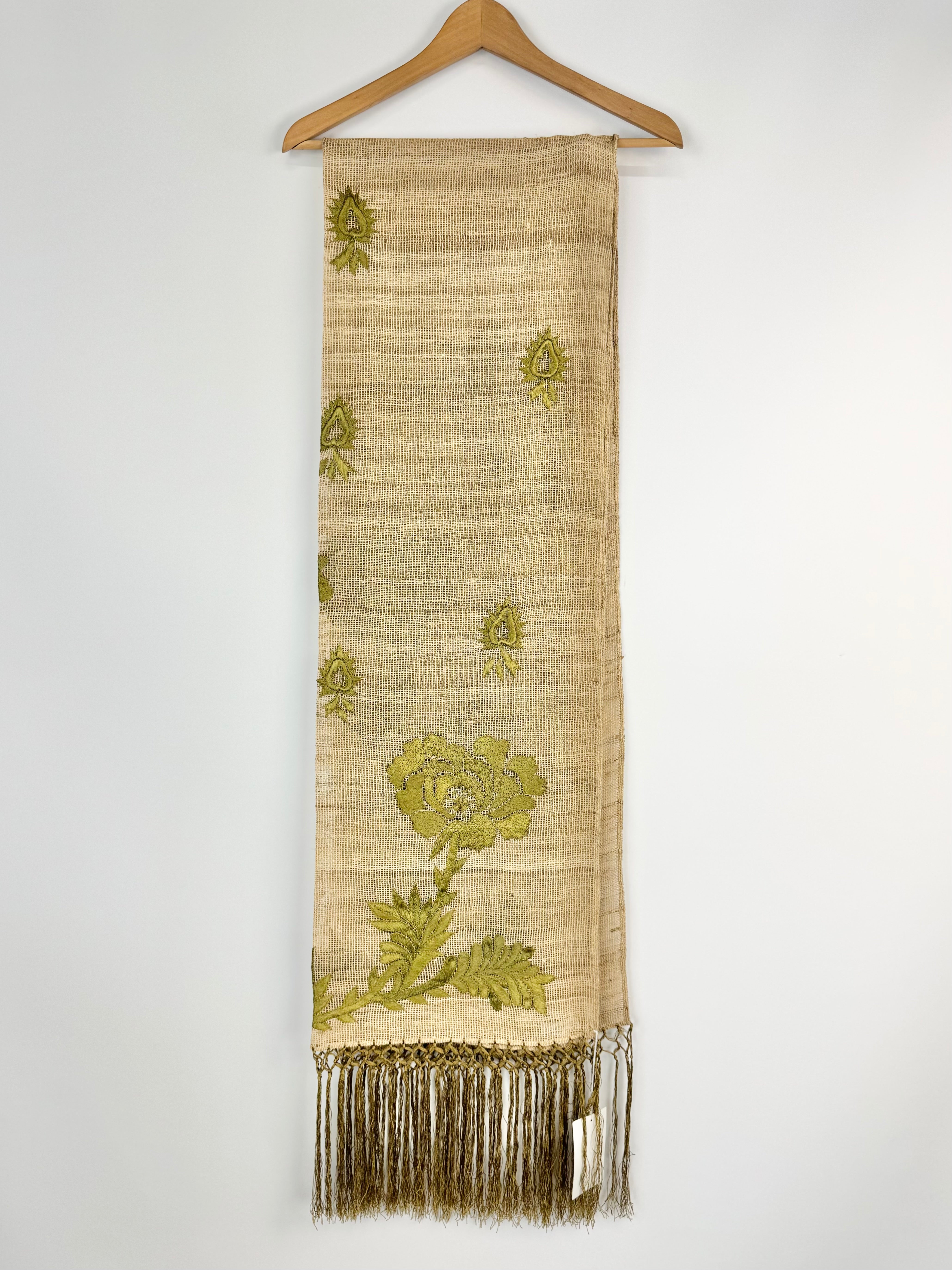 Textile with floral patterns and fringes on a hanger against a white background
