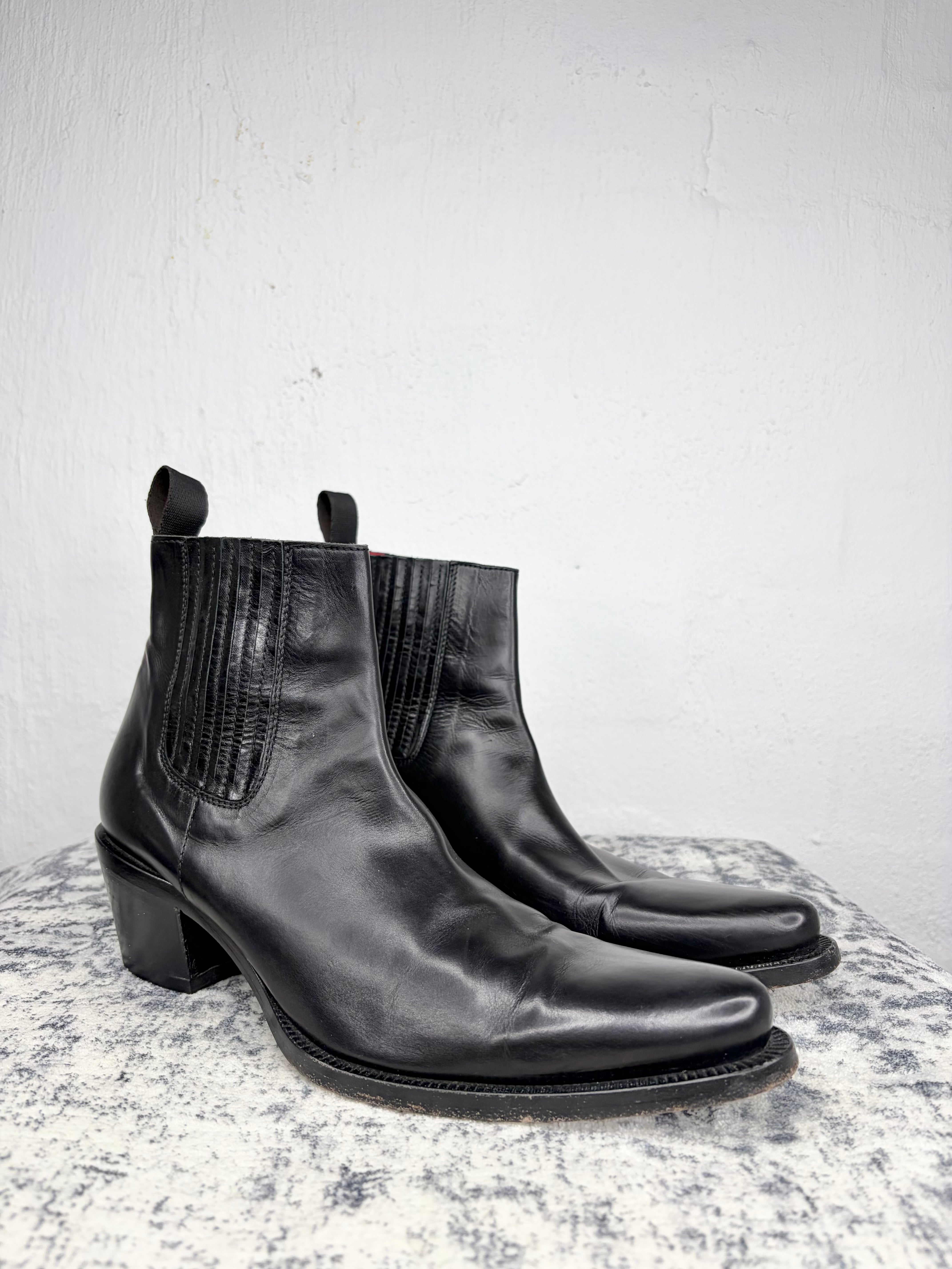 Pair of black leather ankle boots on a light gray background