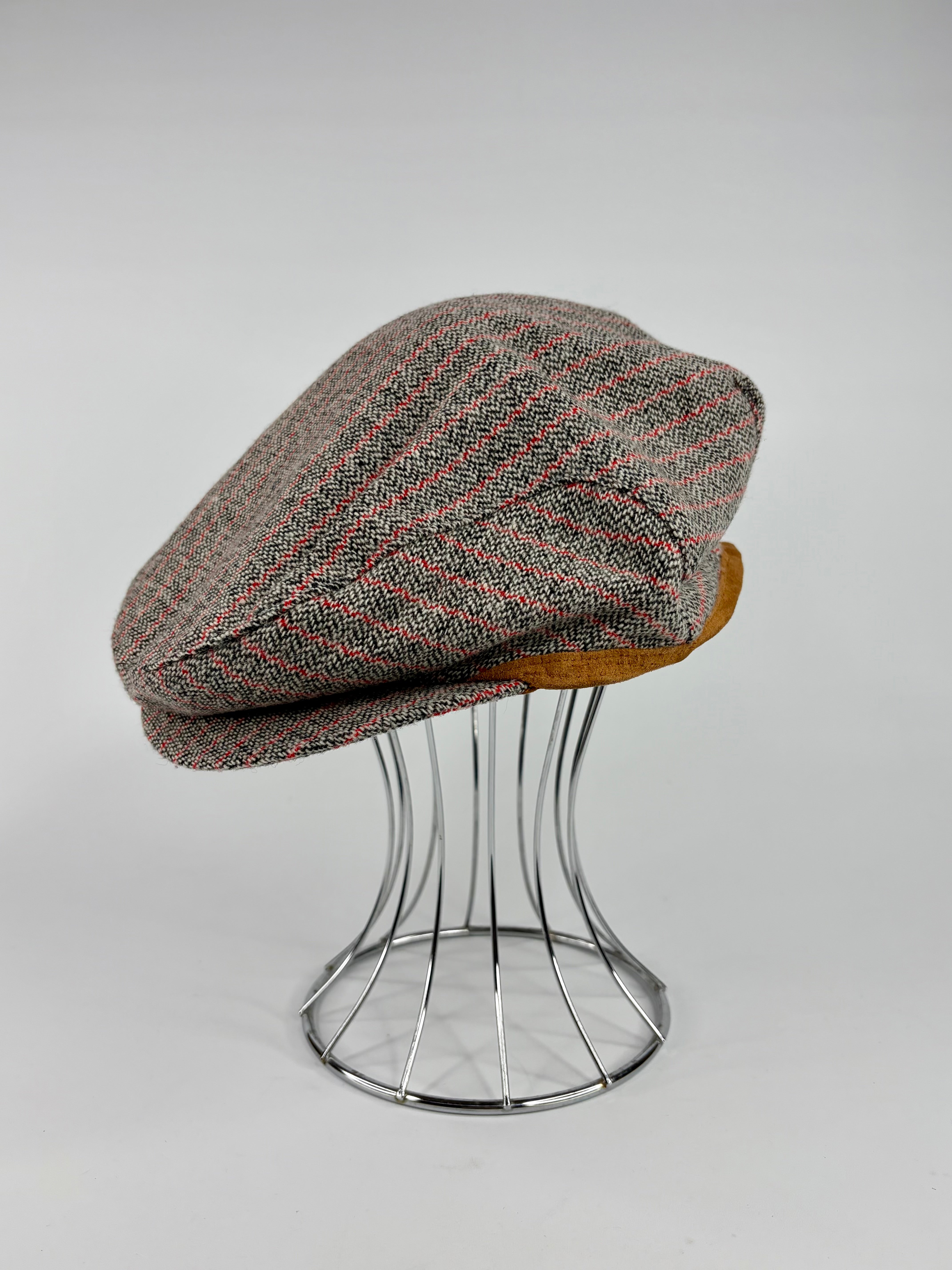 Harris Tweed cap on a metal stand against a white background