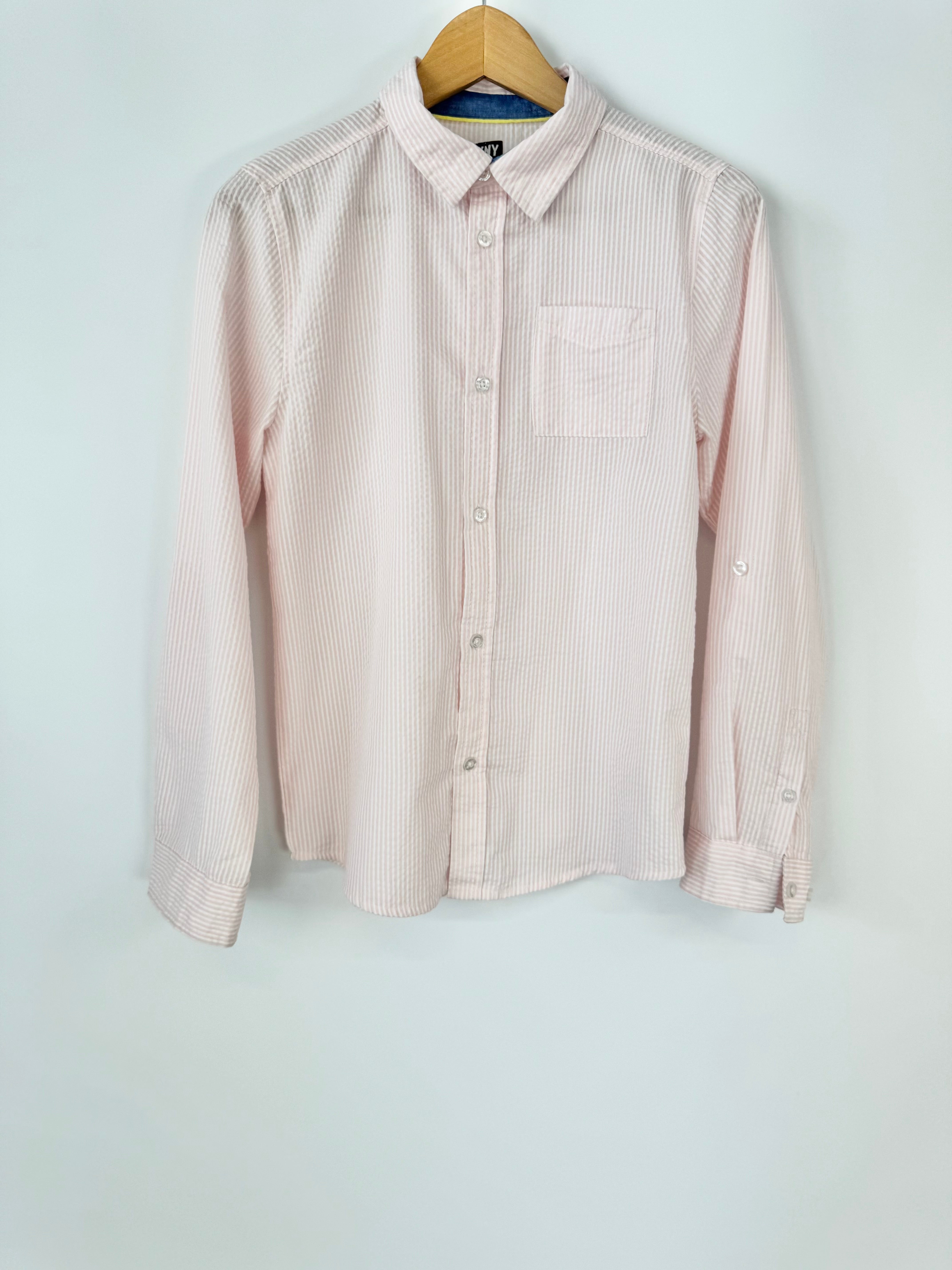 Pink striped shirt on a hanger against a light blue background