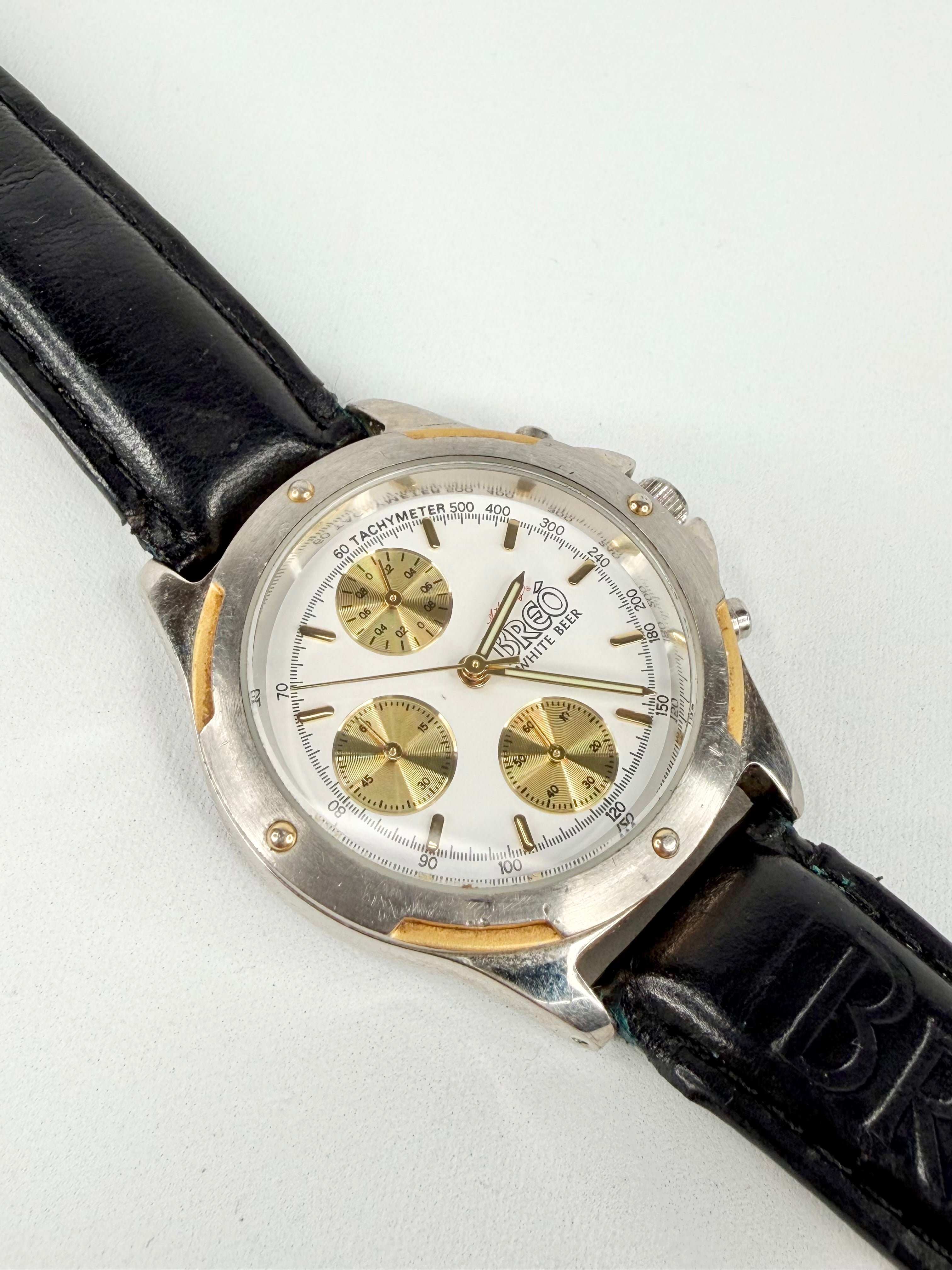Wristwatch with black leather strap and silver and gold dial on a white background