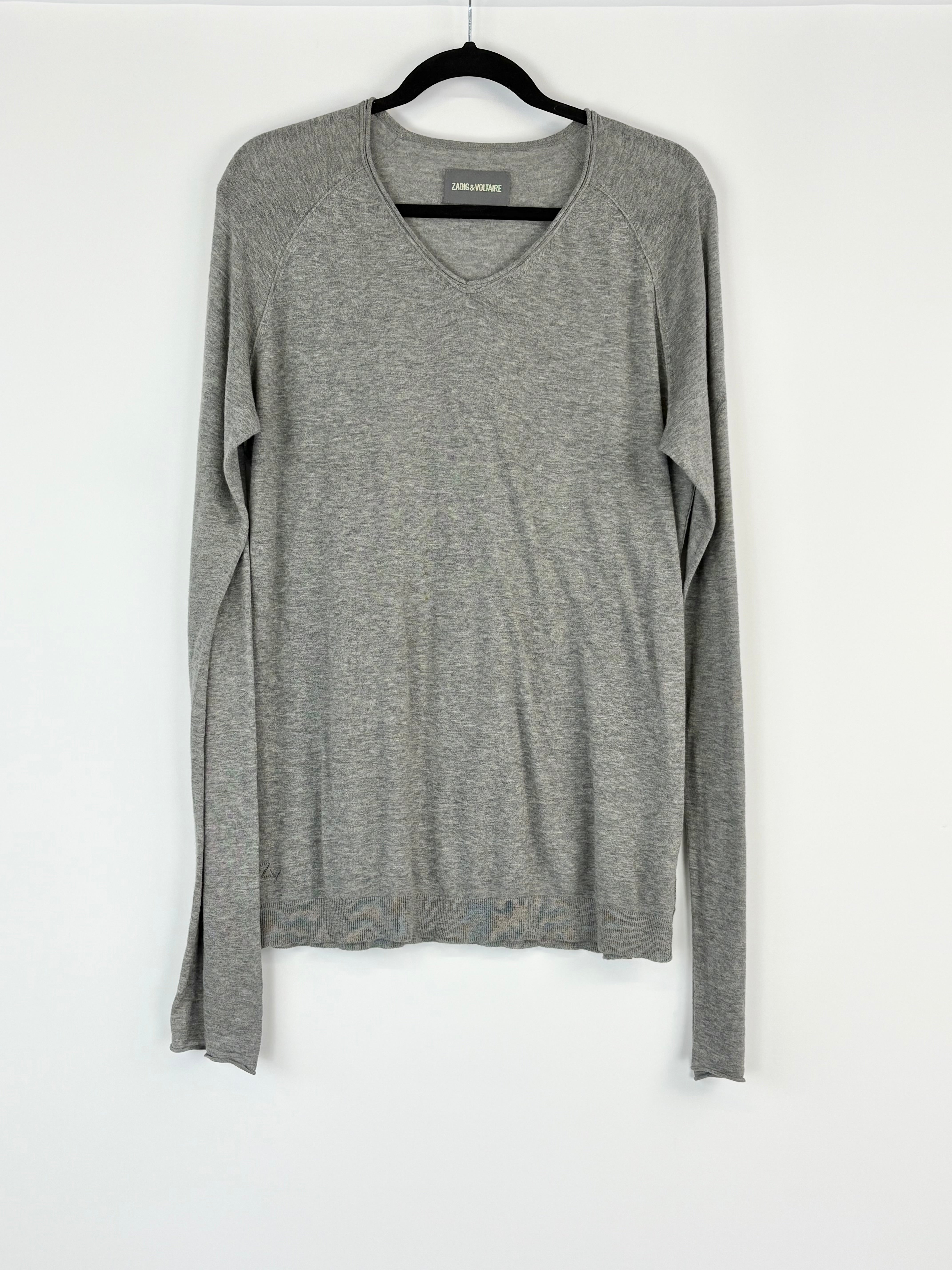 Gray long-sleeve top on a hanger against a white background