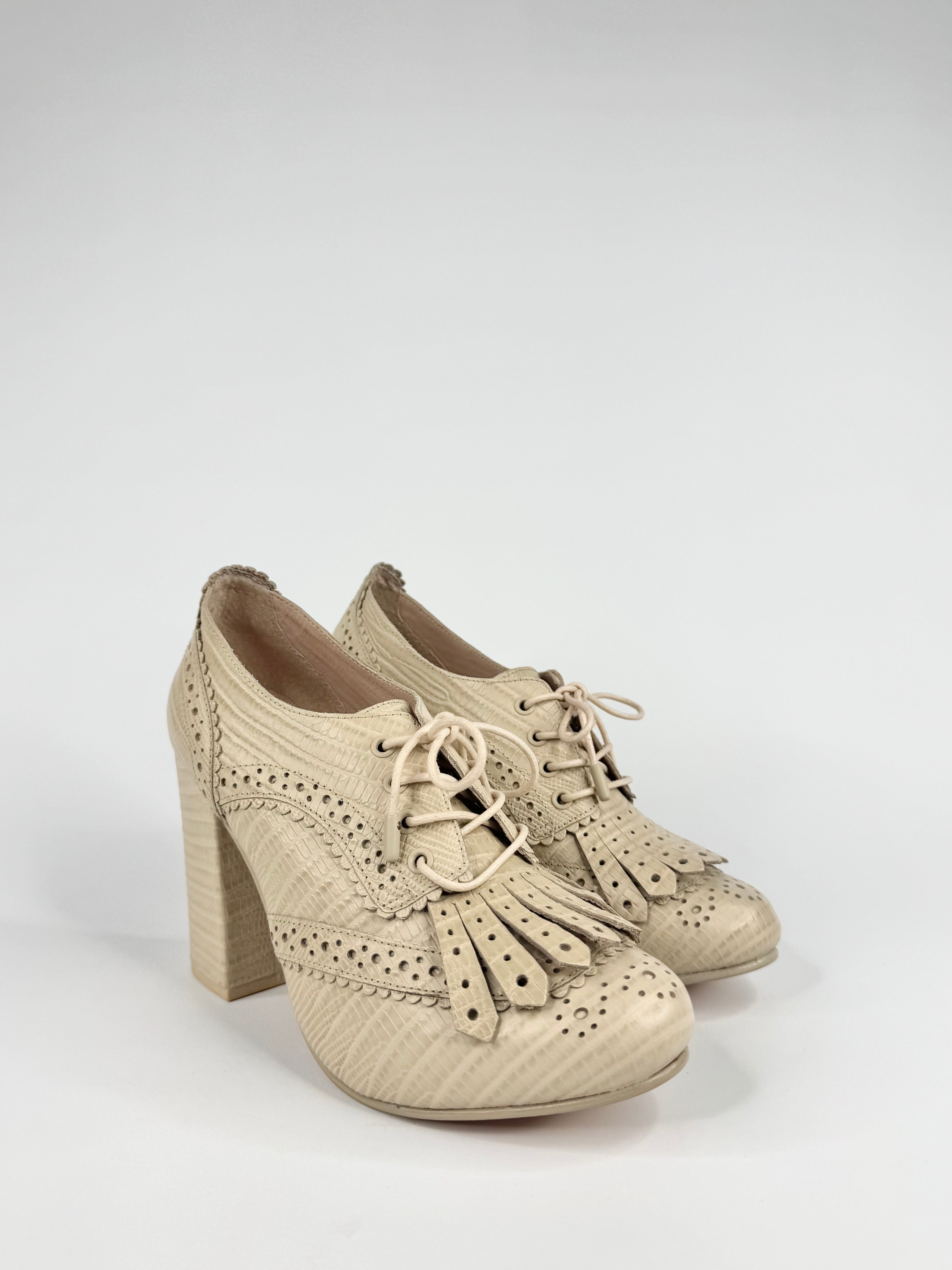 Beige high-heeled shoes with lace-up design on a light gray background