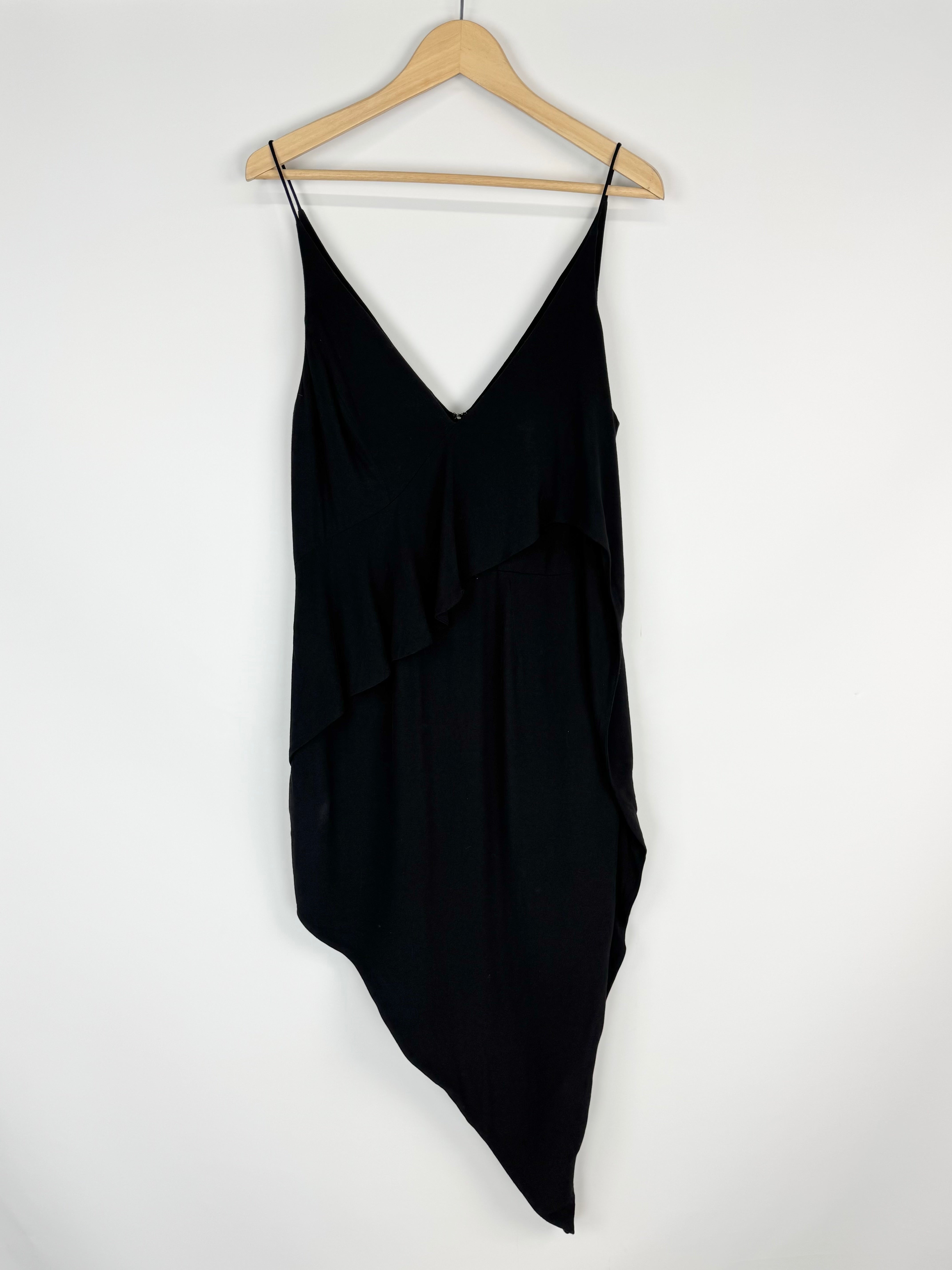 Black slip dress on a wooden hanger against a white background