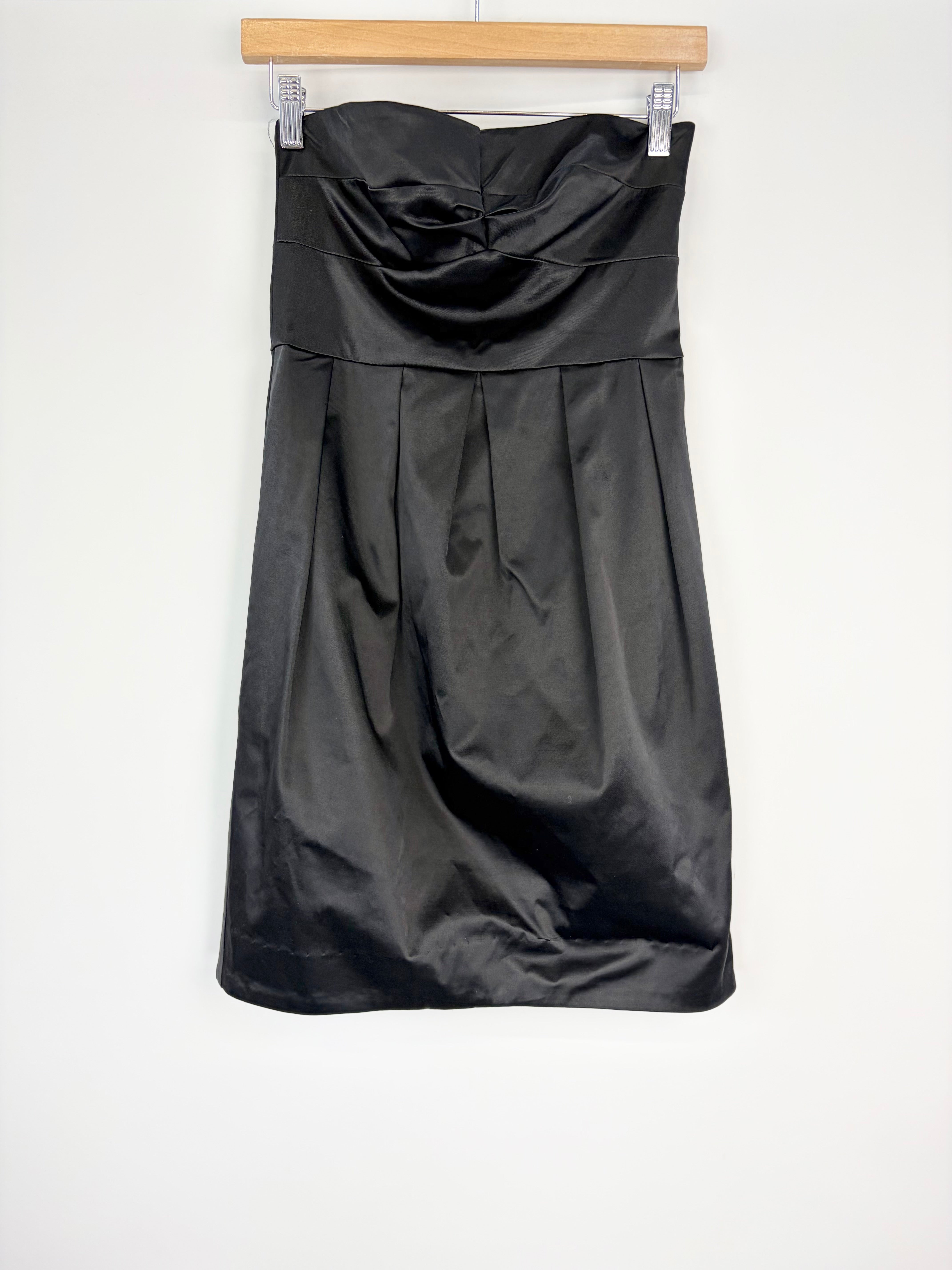 Black strapless dress on a hanger against a white background