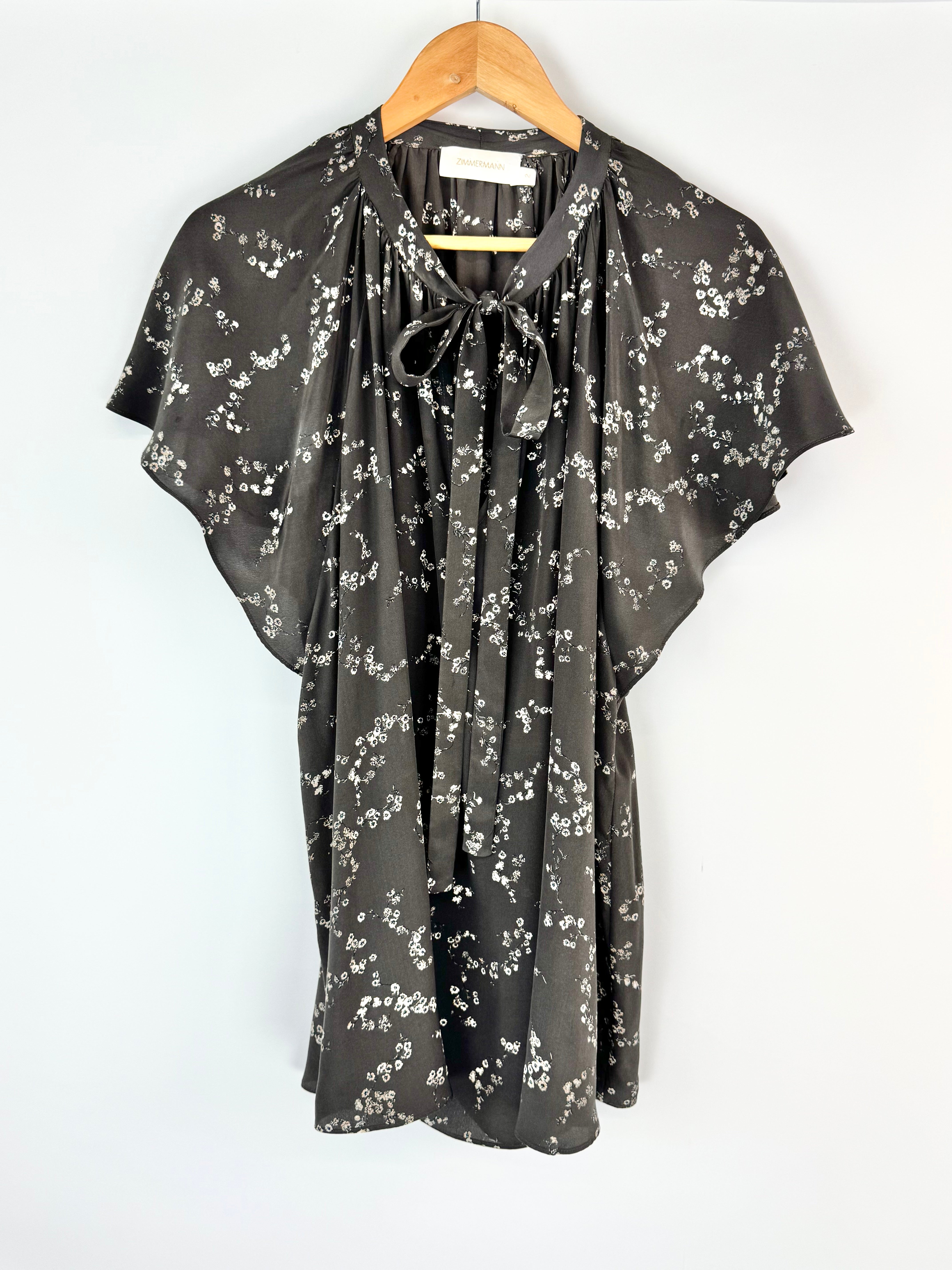 Floral patterned blouse on a hanger against a white background