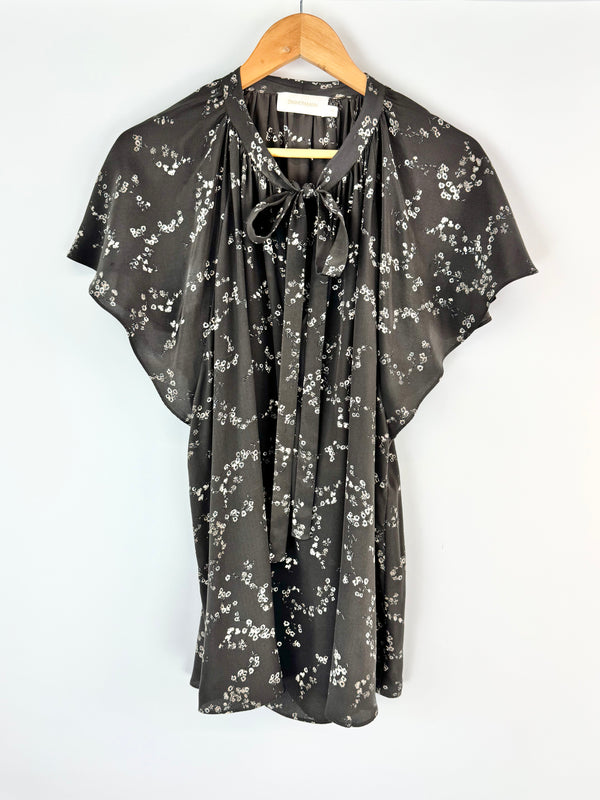 Floral patterned blouse on a hanger against a white background