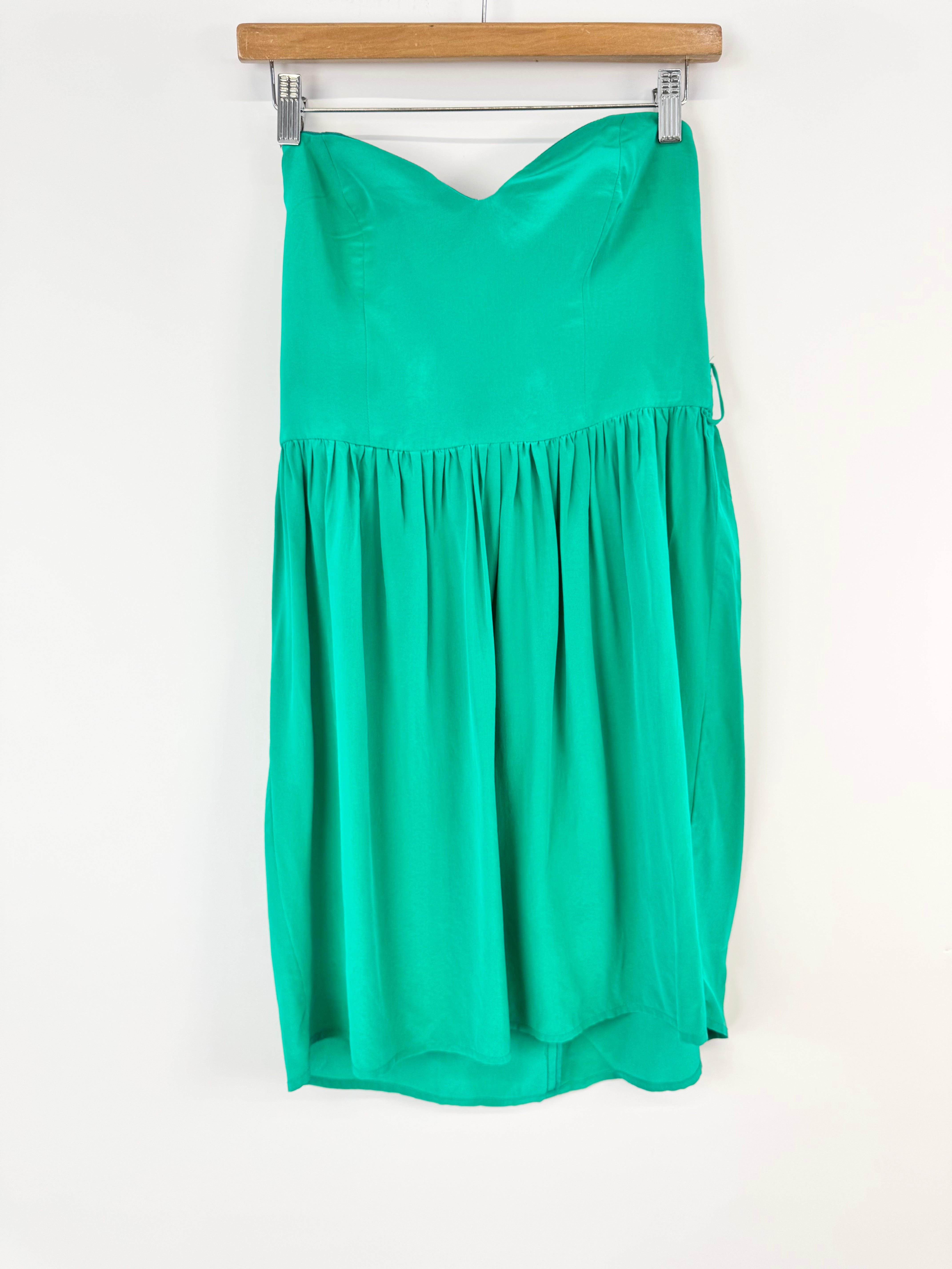 Green strapless dress on a hanger against a white background