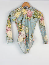 Floral patterned swimsuit on a hanger against a white background