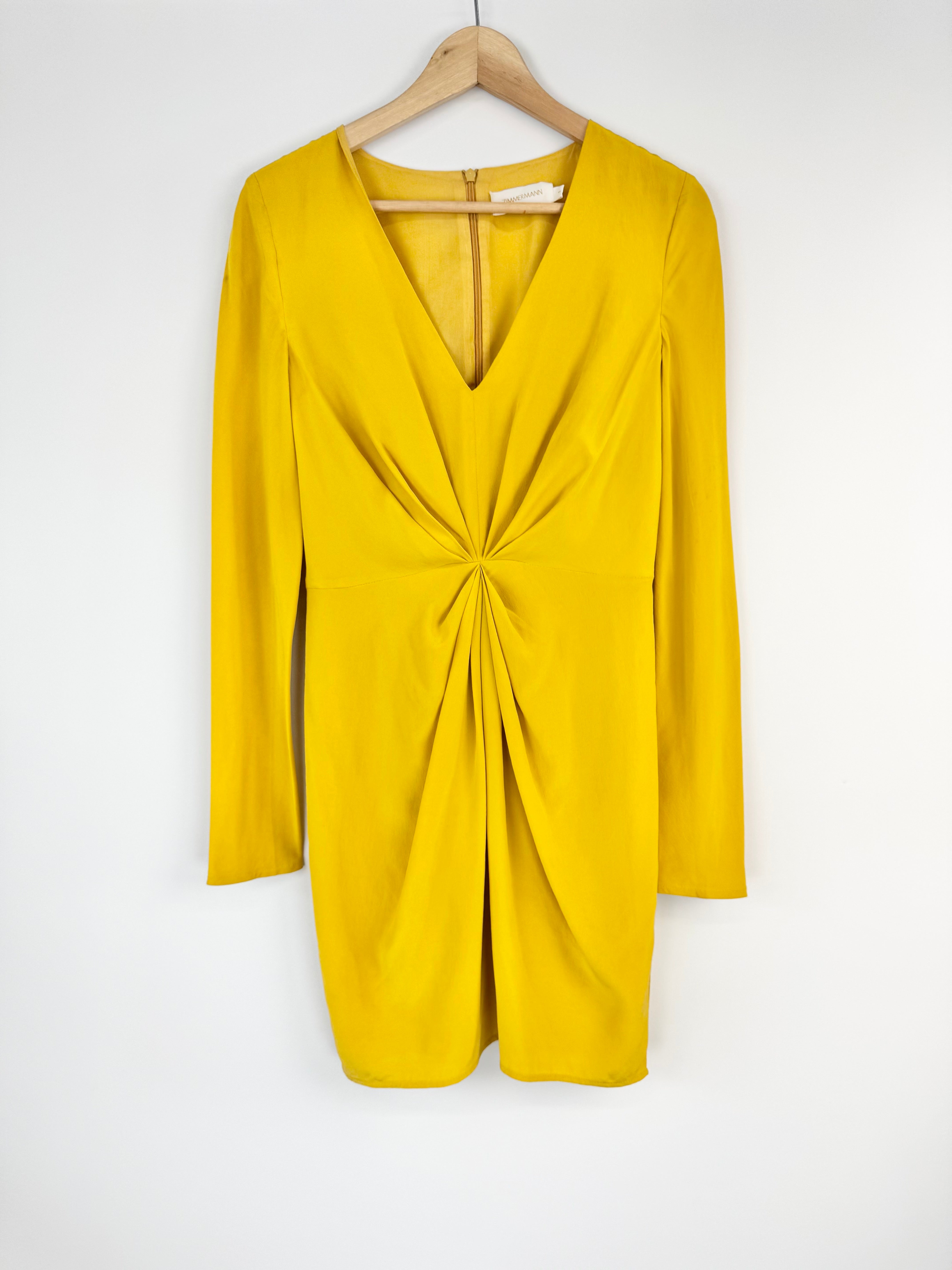 Yellow dress with long sleeves on a hanger against a white background