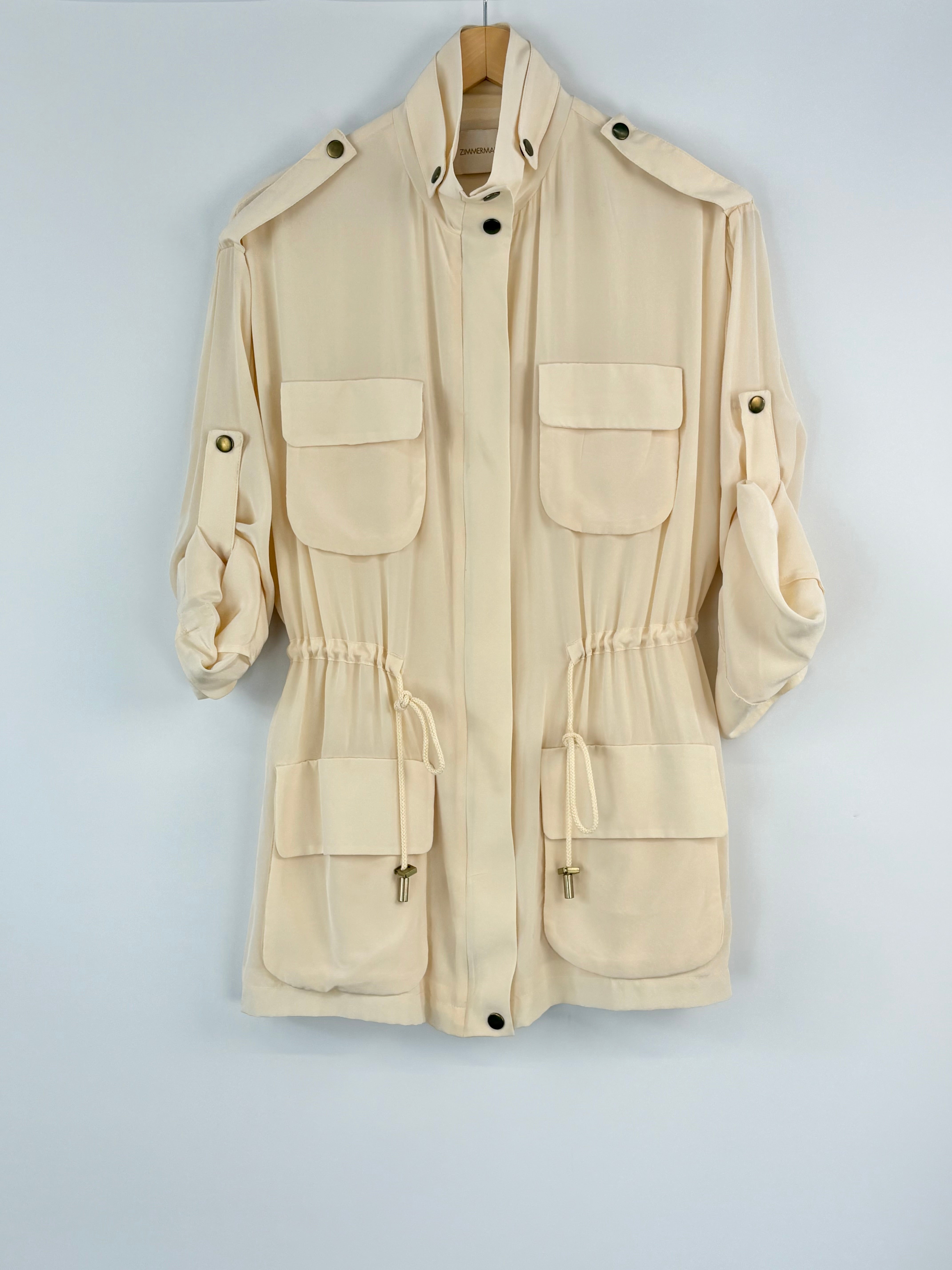 Beige jacket with multiple pockets on a hanger against a light gray background